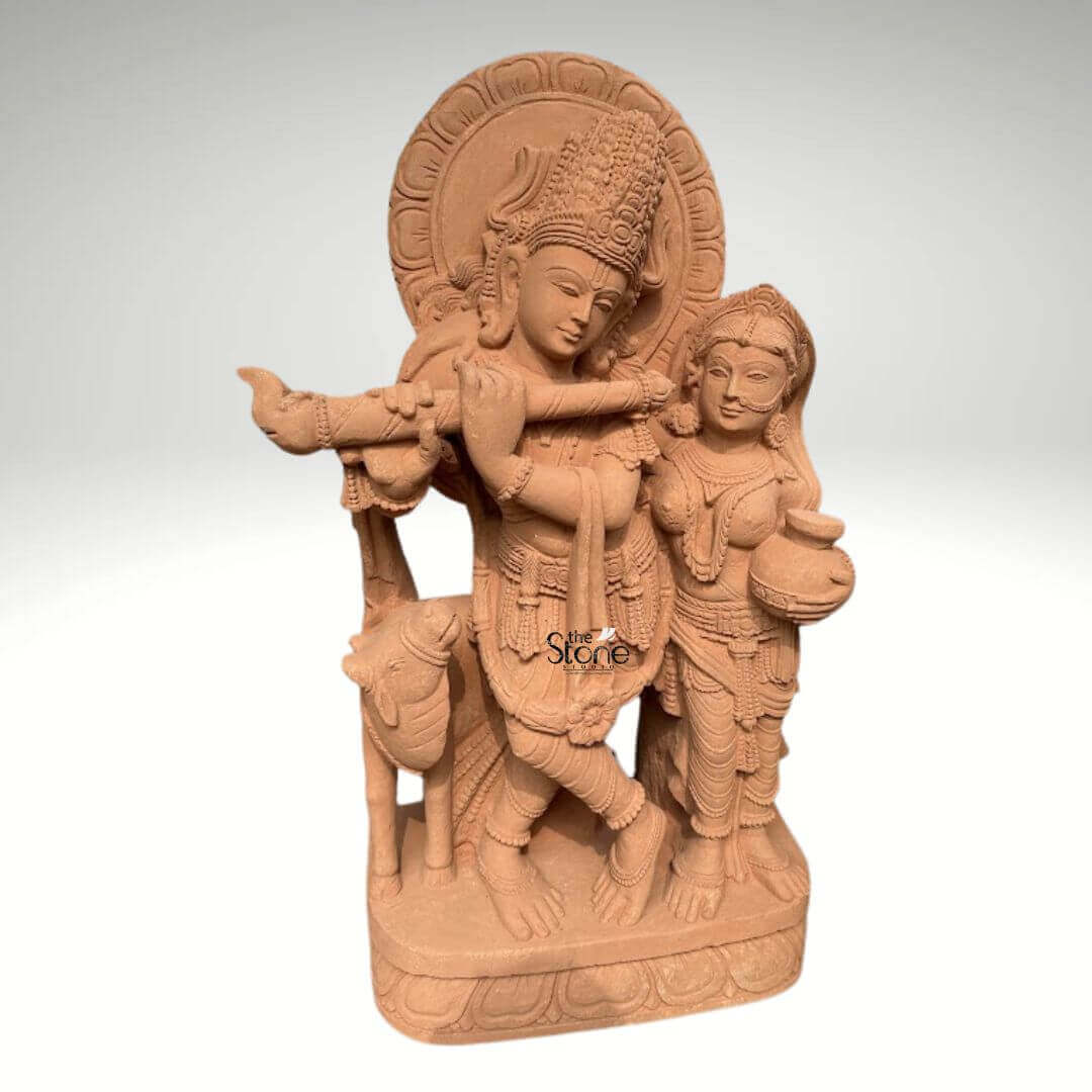 Radha Krishna Statue with Flute in Sand Stone 3ft 4 A breathtaking 3-foot Radha Krishna idol expertly carved from sandstone is showcased against a neutral background serving as the perfect visual for an article about Radha Krishna Idols in Sandstone. The sculpture beautifully depicts Lord Krishna in his iconic pose enchanting the world with his flute a powerful symbol of divine love and harmony. He is regally adorned with an elaborate crown intricate jewelry and flowing garments all exquisitely rendered in the sandstone. Standing gracefully beside him is Radha his eternal consort equally embellished with traditional ornaments holding a pot and gazing lovingly towards Krishna embodying their profound and inseparable bond. The warm earthy hue of the sandstone magnificently enhances the intricate details and the spiritual essence of the carving. Krishna's graceful posture with one leg crossed and Radha's gentle yet dignified stance are sculpted with fluid lines conveying a sense of serene movement and unwavering devotion. Behind their divine figures a circular halo-like structure is intricately carved with traditional patterns further accentuating their divine aura. A charming, small calf is positioned intimately beside Krishna reinforcing the idyllic and pastoral setting often associated with their divine pastimes. Every ornament from Krishna's anklets and bangles to Radha's earrings and necklace is clearly defined demonstrating truly remarkable craftsmanship and attention to detail. The entire divine ensemble rests upon a sturdy multi-layered base also meticulously carved from sandstone featuring delicate lotus petal motifs and other traditional designs. This intricately designed base provides a strong aesthetic foundation and elevates the statue making it a prominent and revered display piece. This 3-foot Sandstone Radha Krishna idol embodies both spiritual beauty and exceptional artistic excellence making it a captivating subject for an article exploring such devotional and intricately crafted sculptures in sandstone.