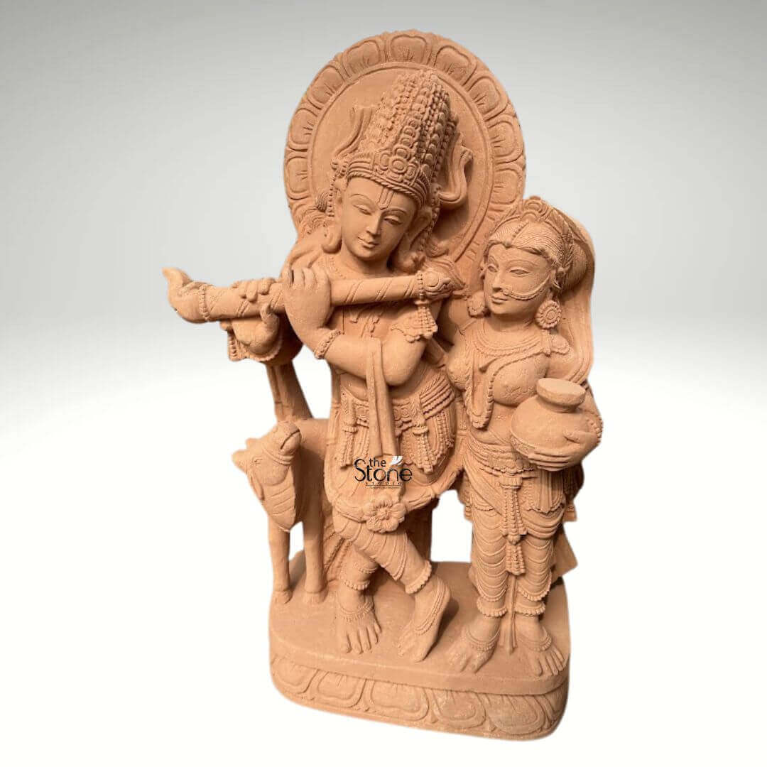 Radha Krishna Statue with Flute in Sand Stone 3ft 5 A magnificent 3-foot sandstone Radha Krishna Murti with flute is elegantly depicted against a neutral background making it an ideal centerpiece for a home temple. The sculpture beautifully portrays Lord Krishna in his iconic posture playing the flute a symbol of divine melody love and spiritual harmony. He is regally adorned with an elaborate crown intricate jewelry and flowing garments all meticulously carved from the rich sandstone reflecting divine artistry. Standing gracefully beside him is Radha his beloved consort equally embellished with traditional ornaments holding a pot her gaze gently directed towards Krishna embodying their profound spiritual connection. The warm earthy hue of the sandstone magnificently enhances the intricate details and the spiritual essence of the carving. Krishna's graceful posture with one leg crossed and Radha's gentle yet dignified stance are sculpted with fluid lines conveying a sense of serene movement and unwavering devotion. Behind their divine figures a circular halo-like structure is intricately carved with traditional patterns further accentuating their divine aura and significance for a home temple. A charming, small calf is positioned intimately beside Krishna, reinforcing the idyllic and pastoral setting often associated with their divine pastimes. Every ornament from Krishna's anklets and bangles to Radha's earrings and necklace is clearly defined demonstrating truly remarkable craftsmanship and attention to detail. The entire divine ensemble rests upon a sturdy, multi-layered base also meticulously carved from sandstone featuring delicate lotus petal motifs and other traditional designs. This intricately designed base provides a strong aesthetic foundation and elevates the Murti making it a prominent and revered display piece. This 3-foot Sandstone Radha Krishna Murti with flute embodies both spiritual beauty and exceptional artistic excellence making it a captivating subject for an article exploring such devotional and intricately crafted statues suitable for a home temple.