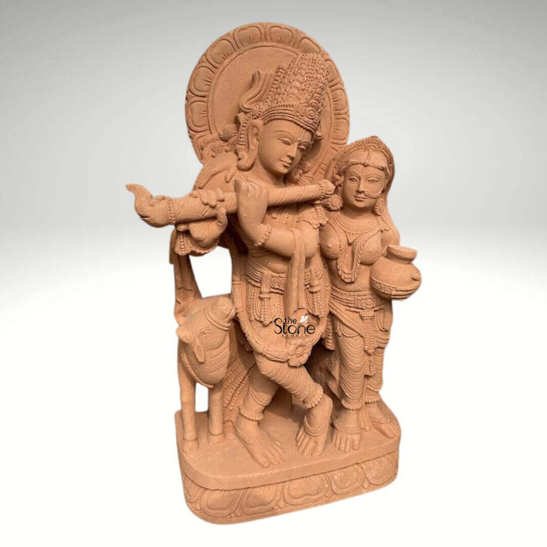 Radha Krishna Statue with Flute in Sand Stone 3ft 6 A magnificent 3-foot sandstone Radha Krishna statue is elegantly depicted against a neutral background making it an ideal choice for garden decor. The sculpture beautifully portrays Lord Krishna in his iconic posture playing the flute a symbol of divine love and harmony elegantly adorned with an elaborate crown intricate jewelry and flowing garments all meticulously carved from the sandstone. Beside him stands Radha his beloved consort equally embellished with traditional ornaments holding a pot her gaze gently directed towards Krishna embodying their profound spiritual connection. The warm earthy tone of the sandstone magnificently enhances the intricate details and the spiritual essence of the carving. Krishna's graceful posture, with one leg crossed and Radha's gentle yet dignified stance are sculpted with fluid lines conveying a sense of serene movement and unwavering devotion. Behind their divine figures a circular halo-like structure is intricately carved with traditional patterns further accentuating their divine aura. A charming, small calf is positioned intimately beside Krishna, reinforcing the idyllic and pastoral setting often associated with their divine pastimes. Every ornament from Krishna's anklets and bangles to Radha's earrings and necklace is clearly defined demonstrating truly remarkable craftsmanship and attention to detail. The entire divine ensemble rests upon a sturdy multi-layered base also meticulously carved from sandstone featuring delicate lotus petal motifs and other traditional designs. This intricately designed base provides a strong aesthetic foundation and elevates the statue making it a prominent and revered display piece. This 3-foot Sandstone Radha Krishna statue embodies both spiritual beauty and exceptional artistic excellence making it a captivating subject for an article exploring such devotional and intricately crafted sculptures suitable for garden decoration.