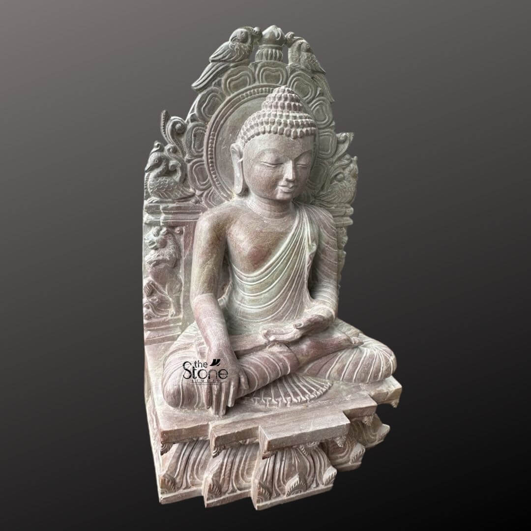 Buddha Statue 8" 2 An exquisite 8-inch Small Buddha Idol carved from pink stone is beautifully presented against a deep dark background ideal for home decor. The Buddha is depicted in a traditional meditative seated posture likely the Dhyana Mudra with his hands gently resting in his lap signifying profound concentration and spiritual peace. His expression is serene with downcast eyes a subtle smile and elongated earlobes all conveying deep wisdom and tranquility. The pink stone Buddha statue features intricate carvings particularly on the elaborate aureole or throne back that frames the deity. This backdrop is adorned with detailed motifs including birds at the top and swirling patterns adding to the idol's sacred aesthetic and artistic richness. The Buddha's hair is meticulously sculpted in tight curls culminating in the ushnisha and his robes are rendered with delicate pleats and folds. The subtle warm pink hue of the stone adds a gentle and inviting quality to the piece making it visually appealing. The statue sits on a multi-tiered base also carved with intricate patterns and what appear to be lotus petal designs. This 8-inch pink stone Buddha idol is a perfect subject for an article on small Buddha statues for home highlighting its suitability for personal altars meditation corners or decorative shelves. The detailed craftsmanship spiritual posture and calming presence make it a significant piece for fostering peace and positive energy within a home. The statue’s compact size combined with its profound artistic and spiritual value makes it an ideal choice for enhancing any interior decor with a touch of serenity and enlightenment.
