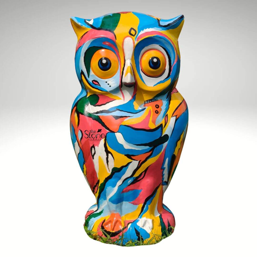 Pop Art Owl Statue 3ft 6 A vibrant hand-painted Pop Art owl statue stands against a seamless light grey studio background. Measuring 36 inches in height the sculpture is a dynamic kaleidoscope of colors featuring abstract swirling patches of hot pink turquoise blue bright yellow orange and green. The overall effect is energetic and playful transforming the realistic form of the owl into a canvas for bold non-representational art. The statue is sculpted in a standing pose with defined ear tufts and large prominent eyes which are also integrated into the abstract color scheme with orange irises and black pupils. The surface of the fibre statue is covered in a rich tapestry of brushstrokes and color blocks giving it a hand-crafted feel. The colors flow into one another without defined outlines creating a fluid pattern that wraps around the entire form including the feathered texture suggested on the chest and the detailed talons at the base. The statue rests on a small integrated green patch hinting at its potential use as a garden sculpture but it is presented here in a clean product shot. This colorful owl statue embodies the principles of Pop Art through its use of bright commercial colors and everyday subject matter elevated to an art object. Its large scale makes it a commanding presence whether displayed indoors as a focal point or outdoors in a garden setting. The tactile quality of the paintwork and the engaging slightly whimsical expression of the owl make it a striking piece of decor. This statue is a perfect example of how art can be integrated into functional spaces serving as a conversation piece that celebrates creativity and color.