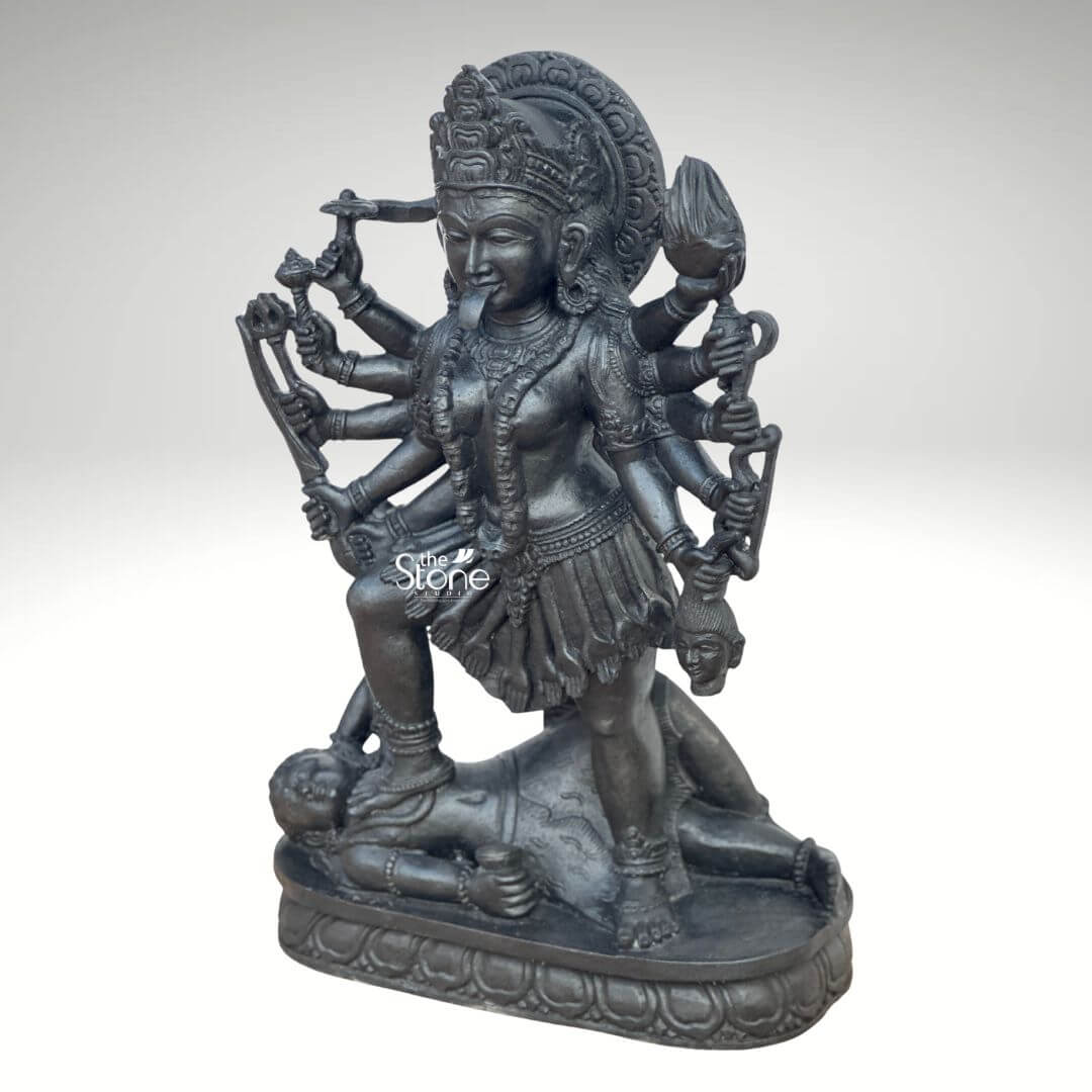 Kali Maa Murti Online 2ft 5 A powerful 2 feet Handcrafted Mahakali Stone Sculpture meticulously carved from dark blackstone stands dramatically against a clean light background highlighting its fierce yet protective form. This 2 feet blackstone Maa Kali statue depicts the formidable goddess Mahakali embodying her destructive and transformative power. She is shown in her iconic stance with her right foot placed upon the reclining figure of Lord Shiva a symbolic representation of divine energy and consciousness. The smooth polished blackstone gives the statue a commanding and ancient presence. Maa Kali is depicted with multiple arms each holding a different weapon or symbolic item signifying her various powers to destroy evil and ignorance. Her tongue protrudes menacingly and her face though fierce also conveys a sense of divine purpose. She wears a crown necklaces and a skirt of skulls or severed arms all intricately carved in the blackstone consistent with traditional iconography. A halo or aureole behind her head further emphasizes her divine status. The intricate details of her jewelry weapons and the expressions on her multiple faces showcase exceptional craftsmanship. The reclining figure of Lord Shiva beneath her foot is also carved with clear detail serene even in this powerful pose representing the balance of cosmic forces. The entire sculpture rests on a multi-tiered lotus-petal shaped base also made of blackstone providing a sturdy and dignified foundation. The overall composition powerfully conveys Mahakali's immense strength her role as a destroyer of evil and her ultimate protective nature. This detailed description effectively connects the visual elements of the Handcrafted Mahakali Stone Sculpture with its spiritual significance and aesthetic qualities making it an ideal representation for an article about a 2 feet blackstone Maa Kali statue.