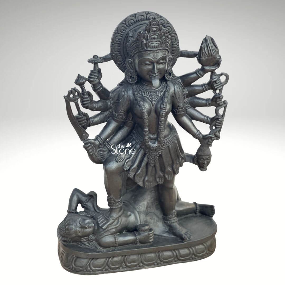 Kali Maa Murti Online 2ft 9 A powerful 2 feet Maa Kali Black Granite Statue meticulously carved from dark blackstone stands dramatically against a clean light background highlighting its fierce yet protective form. This 2 feet blackstone Maa Kali statue depicts the formidable goddess Maa Kali embodying her destructive and transformative power. She is shown in her iconic stance with her right foot placed upon the reclining figure of Lord Shiv a symbolic representation of divine energy and consciousnes perfectly capturing the essence of a Maa Kali Black Granite Statue. The smooth polished surface of the blackstone gleams giving the statue a commanding and ancient presence. Maa Kali is depicted with multiple arms each holding a different weapon or symbolic item signifying her various powers to destroy evil and ignorance. Her tongue protrudes menacingl and her face though fierce also conveys a sense of divine purpose. She wears a crown necklaces and a short skirt all intricately carved in the blackstone consistent with traditional iconography. A halo or aureole behind her head further emphasizes her divine status. The intricate details of her jewelry weapons and the expressions on her primary face showcase exceptional craftsmanship. The reclining figure of Lord Shiva beneath her foot is also carved with clear detail serene even in this powerful pose representing the balance of cosmic forces. The entire sculpture rests on a multi-tiered lotus-petal shaped base also made of blackstone providing a sturdy and dignified foundation. The overall composition powerfully conveys Maa Kali's immense strength her role as a destroyer of evil and her ultimate protective nature. This detailed description effectively connects the visual elements of the Maa Kali Black Granite Statue with its spiritual significance and aesthetic qualities making it an ideal representation for an article about a 2 feet blackstone Maa Kali statue.