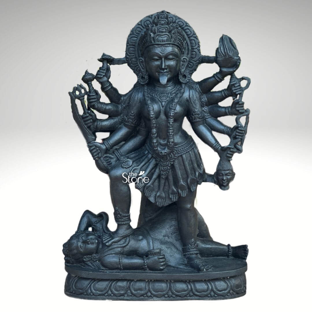 Kali Maa Murti Online 2ft 11 A powerful 2 feet Mahakali Black Stone Statue meticulously carved from dark blackstone stands dramatically against a clean light background highlighting its fierce yet protective form. This 2 feet blackstone Maa Kali statue depicts the formidable goddess Mahakali embodying her destructive and transformative power. She is shown in her iconic stance with her right foot placed upon the reclining figure of Lord Shiva a symbolic representation of divine energy and consciousness perfectly capturing the essence of a Mahakali Black Stone Statue. The smooth polished blackstone gives the statue a commanding and ancient presence. Maa Kali is depicted with multiple arms each holding a different weapon or symbolic item signifying her various powers to destroy evil and ignorance. Her tongue protrudes menacingly and her face though fierce also conveys a sense of divine purpose. She wears a crown necklaces and a short skirt all intricately carved in the blackstone consistent with traditional iconography. A halo or aureole behind her head further emphasizes her divine status. The intricate details of her jewelry weapons (including a sword, trident and severed head and the expressions on her primary face showcase exceptional craftsmanship. The reclining figure of Lord Shiva beneath her foot is also carved with clear detail serene even in this powerful pose representing the balance of cosmic forces. The entire sculpture rests on a multi-tiered, lotus-petal shaped base, also made of blackstone, providing a sturdy and dignified foundation. The overall composition powerfully conveys Mahakali's immense strength, her role as a destroyer of evil, and her ultimate protective nature. This detailed description effectively connects the visual elements of the Mahakali Black Stone Statue with its spiritual significance and aesthetic qualities, making it an ideal representation for an article about a 2 feet blackstone Maa Kali statue.