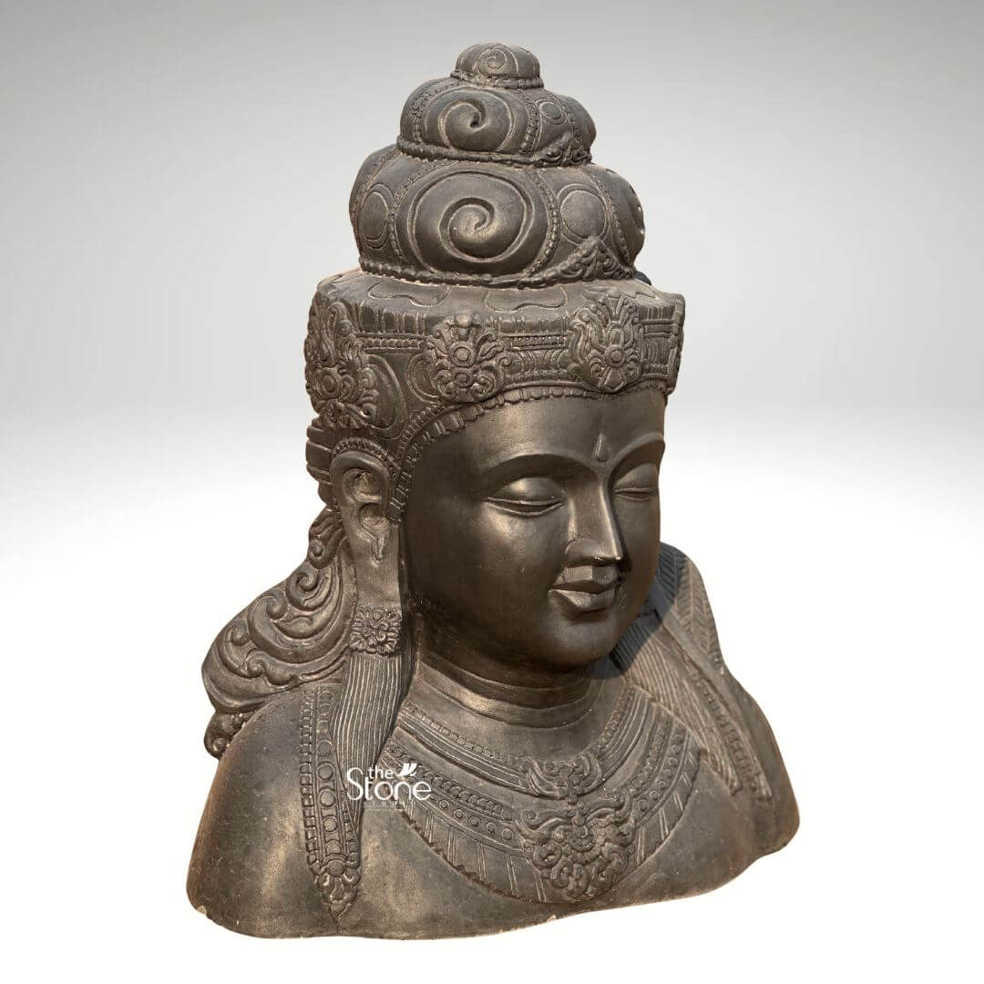 Shiva Bust Statue 30" 6 A striking 2.5 Feet Blackstone Shiva Bust Statue capturing the serene yet powerful essence of Lord Shiva is presented against a clean light background emphasizing its intricate details and dark rich material. This Indonesian Shiva Head Statue portrays Shivas head and upper torso meticulously carved from blackstone which gives the sculpture a profound sense of antiquity and gravitas. His eyes are gently closed in meditation conveying deep introspection and divine tranquility. The smooth polished surface of the blackstone reflects subtle highlights emphasizing the contours of his face and the delicate carving. Shiva is adorned with an elaborate crown intricately designed with swirls and traditional motifs signifying his regal and divine status. His hair is styled in a jatamukuta a coiled ascetic's bun which is characteristic of his iconography. Below the crown fine details are visible in the decorative bands that encircle his forehead. His face, with its well-defined features including a serene expression and full lips evokes a sense of timeless wisdom. Along his chest detailed necklaces and chest plates are carved showcasing traditional Indonesian artistic influences which are key to identifying it as an Indonesian Shiva Head Statue. The bust extends to the upper chest revealing intricately carved adornments and folds of fabric that suggest a flowing garment. The shoulders are broad giving a sense of divine strength and presence consistent with the powerful nature of Lord Shiva. The overall craftsmanship of the 2.5 Feet Blackstone Shiva Bust Statue is exceptional making it a compelling piece of art and devotion. This detailed description effectively connects the visual elements of the blackstone bust with its cultural origin and spiritual significance making it an ideal representation for an article discussing an Indonesian Shiva Head Statue.