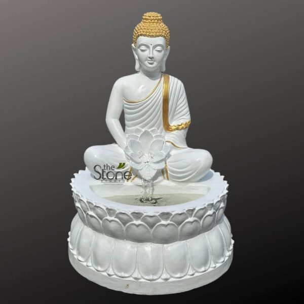 magnificent, highly detailed white Buddha statue, designed as an integrated indoor water fountain, is centered against a plain dark gray background. The Buddha is depicted in a serene, meditative posture, sitting cross-legged in the Padmasana (lotus position) with his hands gently resting in his lap in the Dhyana Mudra (meditation gesture). His expression is profoundly tranquil, with eyes gently cast downwards, elongated earlobes, and a faint, peaceful smile. The statue is primarily crafted from a smooth, pristine white material, likely marble or a high-quality resin, offering a clean and calming aesthetic. Striking gold accents highlight key features: the Buddha's tightly curled hair forms a distinct ushnisha (cranial bump symbolizing wisdom), and a delicate golden sash gracefully drapes over his left shoulder and across his chest, contrasting beautifully with the flowing, intricately pleated white robes that cover his body. Directly in front of the Buddha, at his lap level, the fountain element takes center stage. A large, multi-layered white lotus flower sculpture rises from a shallow, circular basin. From the very heart of this lotus, a gentle stream of clear water gracefully spouts upwards and then cascades back down into the tranquil pool, creating soft, mesmerizing ripples. The entire sculpture rests upon a two-tiered, robust pedestal, also sculpted in pure white, with its layers resembling additional delicate lotus petals, reinforcing the spiritual symbolism of purity and enlightenment. On the lower left side of the fountain's basin, the logo "the Stone STUDIO" is subtly incorporated, suggesting the craftsmanship and origin of this exquisite piece. This elaborate Buddha water fountain embodies peace, mindfulness, and spiritual tranquility, making it an ideal decorative element for creating a zen atmosphere in a meditation space, home altar, living room, or as a sophisticated addition to any interior seeking a blend of aesthetic beauty, calming sounds, and positive energy through spiritual decor.