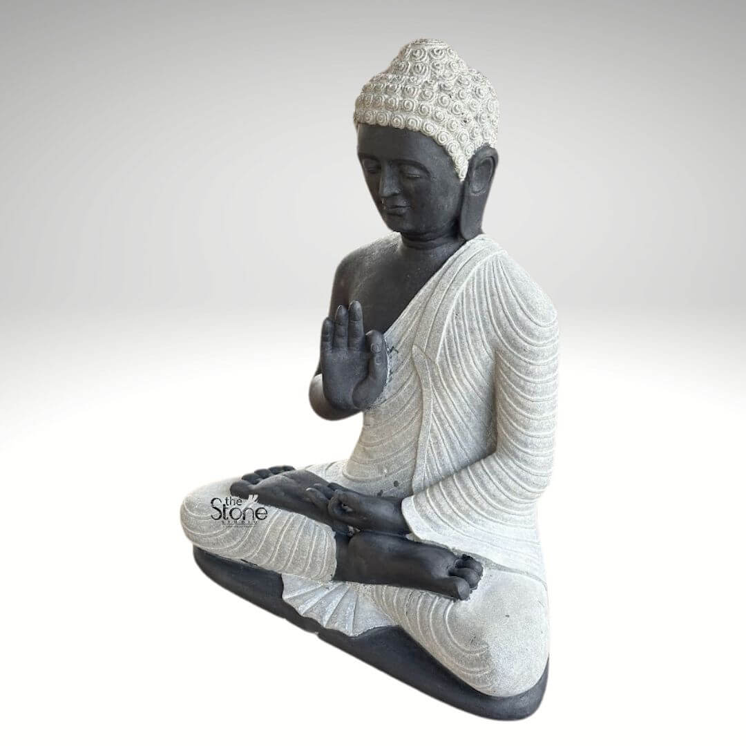 2.5ft Buddha Sculpture for Garden 2 A serene 2.5-foot Buddha statue crafted from black stone with white accents perfect for garden decor as highlighted in the article. The Buddha is depicted in a seated meditative posture likely the Dhyana Mudra or Vitarka Mudra with his right hand raised. His body is sculpted from dark almost black stone giving it a strong grounding presence. The contrast is striking as his robes and the tightly curled hair on his head are rendered in a lighter off-white or grey stone making these features stand out. The robes are draped elegantly with realistic folds and pleats meticulously carved into the lighter stone suggesting softness and flow. The Buddha's face is calm and contemplative with downcast eyes a gentle nose and subtle lips conveying profound inner peace and enlightenment. The tightly curled hair on his head a distinctive characteristic of Buddha imagery is intricately detailed in the lighter stone adding texture and realism to the sculpture. His elongated earlobes another symbolic feature are also visible. The entire statue is sculpted with smooth contours and fine details emphasizing a sense of tranquility and spiritual harmony. The two-tone stone effect—dark for the body and lighter for the robes and hair—creates a visually appealing contrast that enhances the artistic value of the piece. This 2.5-foot black stone Buddha statue is an ideal addition for creating a peaceful and reflective corner in any garden embodying the spiritual and aesthetic qualities discussed in the article on garden decor.