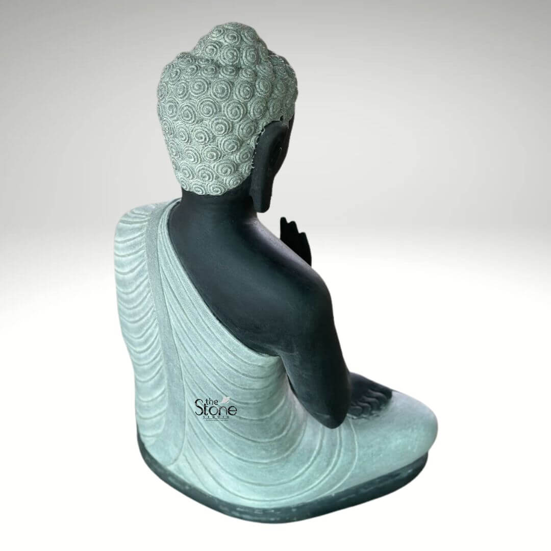 2.5ft Buddha Sculpture for Garden 5 A serene 2.5-foot dual-color Buddha statue crafted from black stone with contrasting lighter stone for the robes and hair viewed from a rear-right angle as detailed in an article about such sculptures. The Buddha is depicted in a seated meditative posture with his right hand gently raised in a mudra and his left hand resting in his lap. The main body of the statue including his back right arm and exposed skin is sculpted from a deep almost black stone providing a strong grounding presence. The robes which gracefully drape over his left shoulder and cover his lower body are rendered in a contrasting lighter off-white or light grey stone. The meticulous carving of the robes showcases realistic flowing folds and pleats suggesting the soft drape of fabric and adding a sense of serenity and refined detail. The tightly curled hair on his head a distinctive iconographic feature is intricately textured in the lighter stone with individual curls clearly defined adding depth and authenticity to the sculpture. His elongated earlobes are also visible. The dual-color effect of the black and lighter stone creates a striking visual contrast that enhances the artistic appeal and spiritual essence of the piece. The smooth contours and fine details throughout the sculpture emphasize a deep sense of tranquility and spiritual harmony. This 2.5-foot Buddha statue is an ideal piece for personal contemplation meditation spaces or as a distinguished decorative element embodying the peaceful and enlightened nature of the Buddha as discussed in the accompanying article.