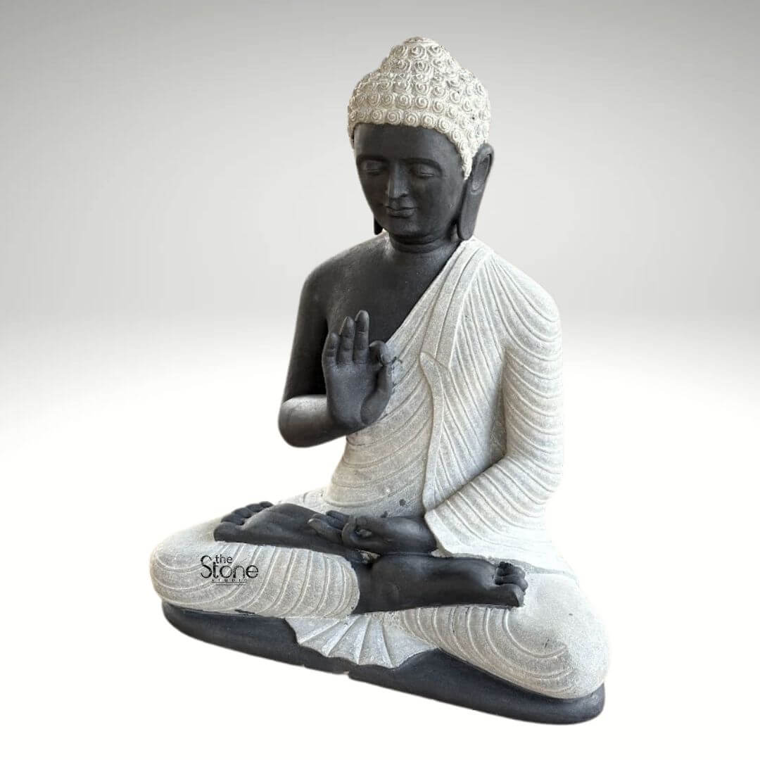 2.5ft Buddha Sculpture for Garden 8 A serene 2.5-foot garden decor Buddha statue meticulously crafted from black stone with elegant white accents depicted in a classic meditative posture as featured in an article about garden decor Buddha statues. The statue presents the Buddha seated cross-legged with his right hand raised in the Vitarka Mudra and his left hand resting in his lap in the Dhyana Mudra. The body is sculpted from a dark almost black stone providing a strong grounding presence while his robes and the tightly curled hair on his head are rendered in a contrasting lighter off-white or grey stone highlighting these features. The robes are intricately carved with flowing realistic folds and pleats suggesting the soft drape of fabric adding a sense of serenity and refined detail to the sculpture. The Buddha's face is characterized by a calm and contemplative expression with downcast eyes a gentle nose and subtle lips embodying profound inner peace and enlightenment. The tightly curled hair a distinctive iconographic feature is intricately textured in the lighter stone adding depth and authenticity. His elongated earlobes another symbolic feature are also clearly visible. The overall design of this 2.5-foot black stone Buddha statue showcases a harmonious blend of two contrasting stone colors enhancing its visual appeal and artistic merit. The smooth contours and fine details throughout the sculpture emphasize a deep sense of tranquility and spiritual harmony making it an ideal piece for creating a peaceful and reflective corner in any garden. This statue perfectly aligns with the article's theme of garden decor Buddha statues offering both aesthetic beauty and a spiritual focal point for outdoor spaces.