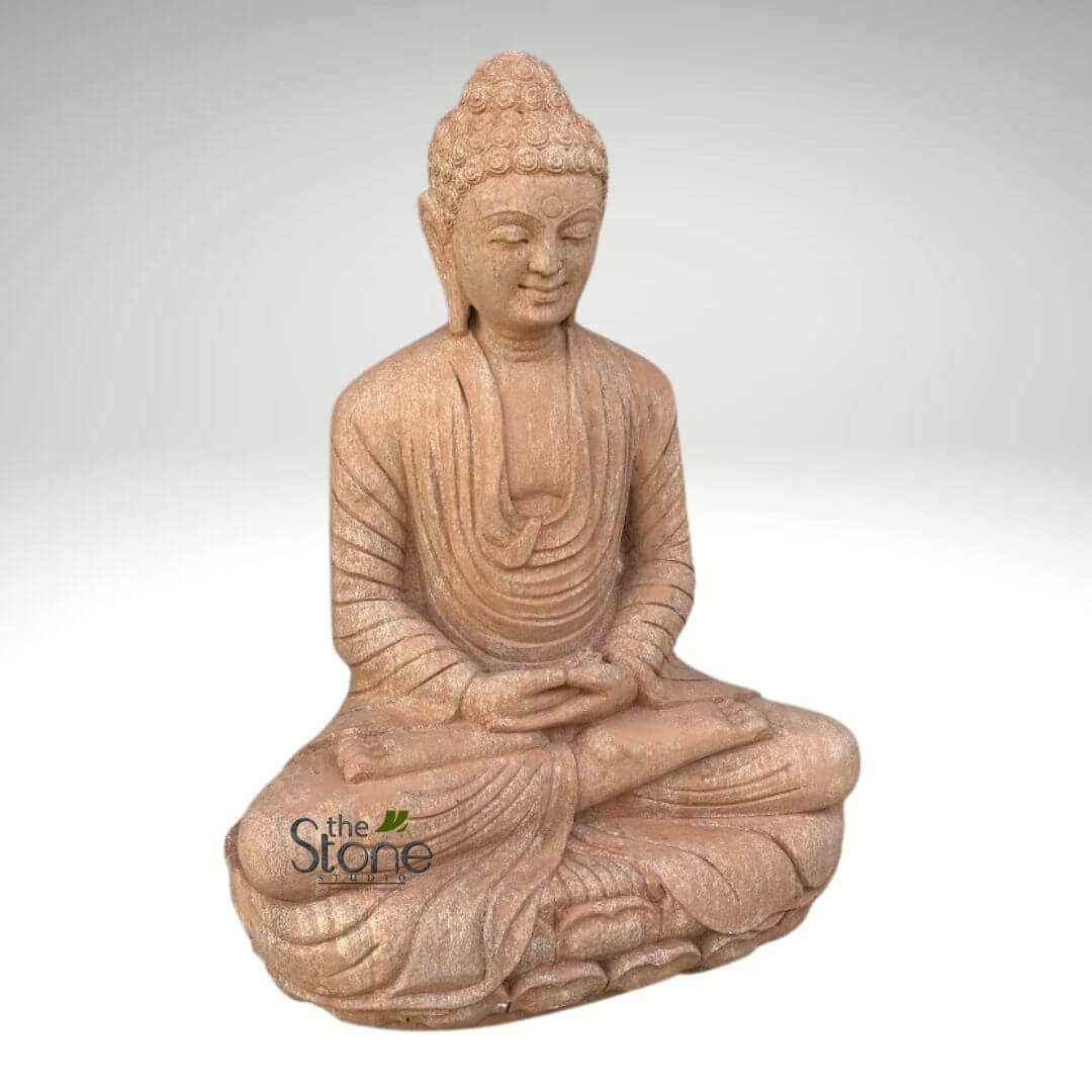 30 inches Garden Buddha Statue 5 serene and meticulously crafted reddish-brown stone Buddha statue is centered in the frame, depicted in a full-lotus seated meditation pose (Padmasana). The statue exudes a profound sense of peace and tranquility, embodying the essence of spiritual contemplation and mindfulness. The Buddha's face is sculpted with a gentle, benevolent smile, and his eyes are softly closed or downcast, conveying a state of deep meditation. His elongated earlobes, a traditional symbol of wisdom and detachment, are subtly carved. The head is adorned with numerous tight, finely detailed curls that ascend to form the Ushnisha, representing his enlightened wisdom and spiritual insight. His hands rest gracefully in his lap, palms open and upward, with the right hand placed over the left, forming the Dhyana Mudra, a gesture symbolizing meditation, concentration, and the attainment of spiritual perfection. The simple, flowing monastic robe is intricately draped, showing realistic folds and creases that highlight the natural, tactile texture of the stone. The material appears to be a sandy or terracotta-colored stone, possibly sandstone, giving the sculpture an earthy, ancient, and grounded aesthetic. The statue is presented against a clean, minimalist background that transitions from a light gray at the top to a pure white at the bottom, isolating the sculpture and emphasizing its form and spiritual presence without distraction. A discreet watermark for "the Stone Studio" is visible in the lower left corner, indicating the origin of this artisan piece. This detailed image effectively conveys themes of inner peace, spiritual harmony, and the timeless beauty of Buddhist art and stone craftsmanship, making it ideal for content related to meditation practices, spiritual decor, garden features, or artisan stone products.