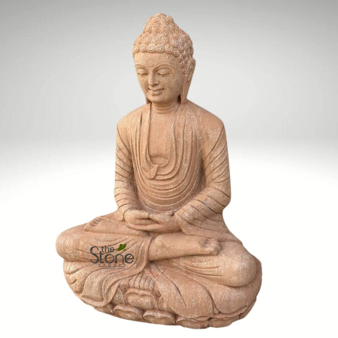30 inches Garden Buddha Statue 2 beautifully crafted Buddha statue, rendered in an earthy, light brown or terracotta-hued stone, stands prominently in the center of the frame against a clean, plain gradient background of light gray to white. The figure is seated in the traditional lotus position (Padmasana), symbolizing deep meditation and enlightenment, with his legs crossed and feet resting on the opposite thighs. His expression is one of profound serenity and tranquility, with eyes gently downcast in a contemplative gaze and a subtle, compassionate smile gracing his lips. His hair is intricately detailed, depicted in tight, curled coils that form the ushnisha—a cranial bump at the crown of his head signifying wisdom and spiritual insight. The delicate drapery of his monastic robes is sculpted with soft, flowing folds and creases that drape gracefully over his left shoulder and torso, highlighting the artisan's skill in capturing fabric movement in stone. His hands rest gently in his lap in the Dhyana Mudra (meditation gesture), with palms upward and fingers lightly touching, signifying concentration, spiritual balance, and the attainment of enlightenment. The overall texture of the stone appears somewhat coarse and natural, suggesting a weathered or handcrafted quality, making it an ideal piece for both indoor spiritual spaces and outdoor garden decor. A subtle watermark for "the Stone Studio" with a green leaf design is visible in the lower-left corner, indicating the origin or artisan behind this exquisite spiritual sculpture, likely connecting to content about stone craftsmanship, bespoke statues, or meditation aids.