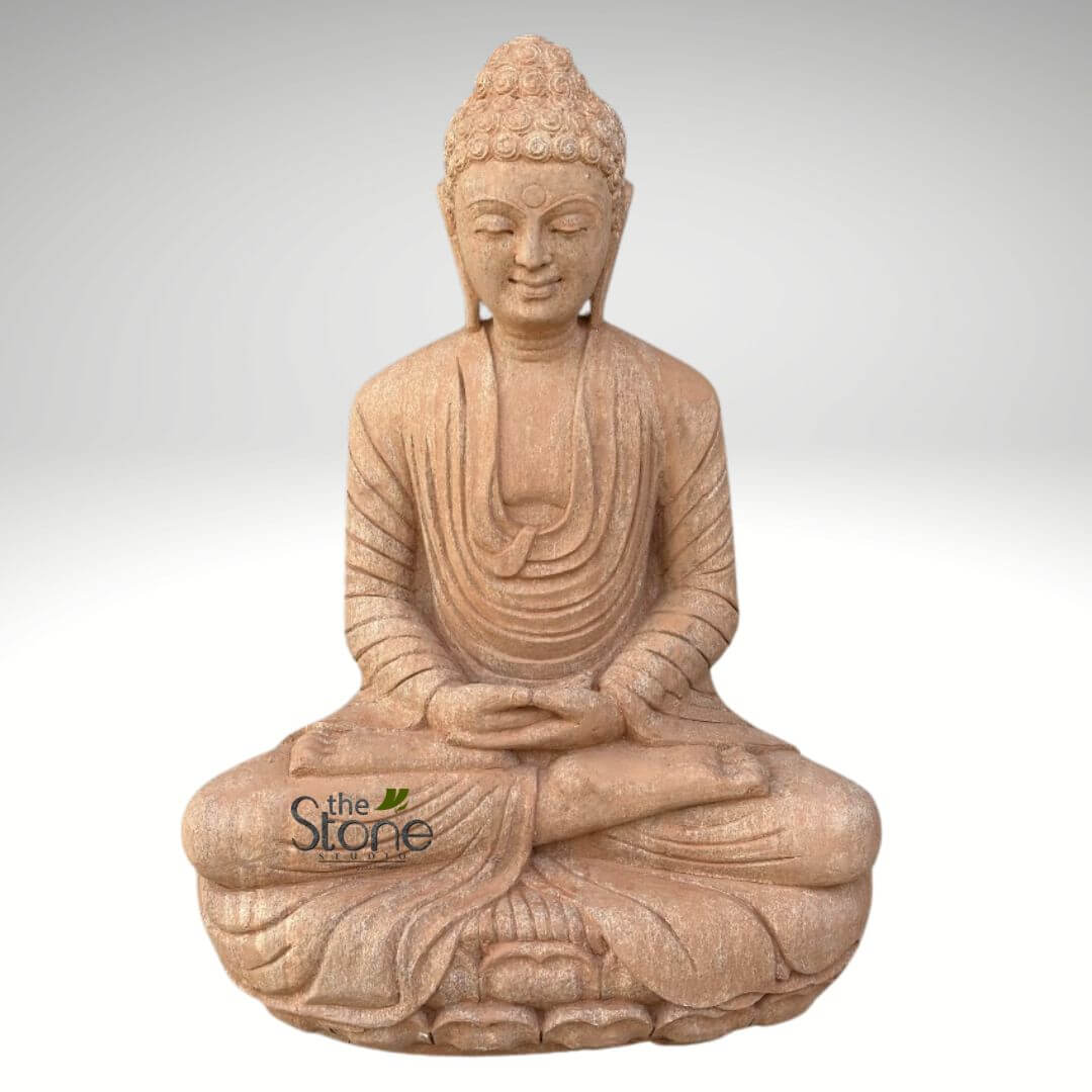 30 inches Garden Buddha Statue 1 beautiful, intricately carved Buddha statue made from natural sandstone, showcasing an earthy, light reddish-brown hue and a subtly textured surface that suggests a rustic, handcrafted feel. The Buddha is depicted in a full meditative posture, known as Padmasana or the lotus position, with legs crossed and feet resting on the opposite thighs, conveying stability and a grounded presence. His hands are gently placed in his lap, palms facing upwards, forming the Dhyana Mudra, a classic gesture of meditation and concentration, symbolizing spiritual enlightenment and inner peace. The figure exudes a profound sense of serenity and mindfulness; the eyes are gently closed or downcast, and a faint, benevolent smile plays on his lips, indicating deep contemplation. His head features tightly curled hair (or representations of curls) and a distinct Usnisha (cranial bump), which symbolizes wisdom and enlightenment. Elongated earlobes, a traditional characteristic, frame his peaceful face. He is clad in flowing monastic robes, meticulously sculpted with deep, naturalistic folds that drape gracefully over his shoulders, arms, and body, adding to the statue's realistic yet spiritual aesthetic. The statue sits upon a finely detailed lotus pedestal, a common and significant symbol of purity, spiritual awakening, and rebirth in Buddhist art. Against a clean, softly graduated white and light gray background, the statue stands out prominently, emphasizing its exquisite form and detail. In the lower left quadrant, "the Stone Studio" logo is subtly visible, indicating the artisan or seller. This handcrafted stone Buddha statue embodies tranquility and mindfulness, making it an ideal representation for articles discussing spiritual practices, home or garden decor, meditation, Zen principles, or the timeless artistry of religious and cultural stone sculpture. It visually communicates a sense of calm and spiritual devotion.
