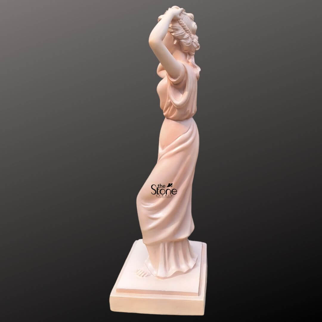 Angel Lady Statue for Resorts 5.5 Feet 2 A side-profile view of an elegant 5.5-foot Angel Lady Statue, masterfully crafted from durable fibre for high-end resort and garden decor. The life-sized classical figure is depicted in a graceful standing posture, with her hands raised behind her head in a natural, serene gesture. Clad in a floor-length, Grecian-style robe, the sculpture features expertly detailed flowing drapery that adds a sense of movement and sophistication. The statue has a smooth, warm pale terracotta finish and stands on a matching square-tiered base. At 5.5 ft tall, this fibre statue is a perfect choice for enhancing the aesthetic appeal of luxury resort landscapes, grand hotel lobbies, or outdoor garden sanctuaries, offering a blend of classical beauty and modern material longevity.