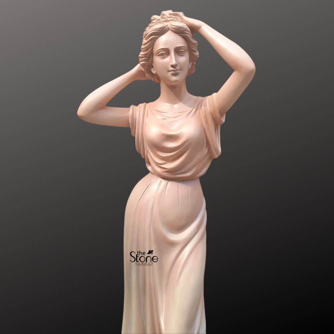 Angel Lady Statue for Resorts 5.5 Feet 6 An elegant 5.5-foot fibre statue of a graceful Angel Lady, designed as a sophisticated centerpiece for outdoor landscapes, gardens, and resorts. The classical female figure is depicted in a tranquil pose, with her hands raised delicately toward her wavy, up-styled hair. She has a serene, gentle facial expression that exudes a sense of calm and beauty. The statue is draped in a sleeveless, floor-length gown featuring masterfully sculpted, flowing folds that give the material a realistic, cloth-like appearance. Finished in a smooth, light peach-toned hue, this life-sized fibre sculpture offers the beauty of traditional stone with the advantage of being weather-resistant and lightweight for outdoor placement. Its majestic 5.5 ft height and timeless aesthetic make it an ideal choice for grand entryways, poolside areas, or lush garden retreats.