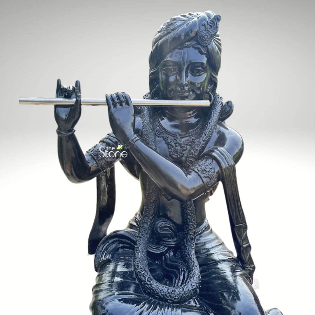 Lord Krishna with Cow Fibre Statue 4ft 2 An upper-body view of an exquisitely crafted Lord Krishna fibre statue with a radiant high-gloss black finish, showcasing a sophisticated and elegant design. The Hindu deity is depicted with a peaceful and meditative expression, gracefully holding a silver-toned flute to his lips in his iconic playing posture. He is adorned with intricate traditional ornaments, including an elaborate turban with a central crest, layered necklaces, and armlets featuring fine relief patterns. The reflective surface of the glossy black fibre sculpture highlights the detailed craftsmanship of the attire and sacred garlands. This durable and lightweight Krishna murti captures the divine essence of the cowherd god, serving as an auspicious and artistic centerpiece for home temple decor, luxury foyers, or garden landscapes where he is traditionally paired with a sacred cow.