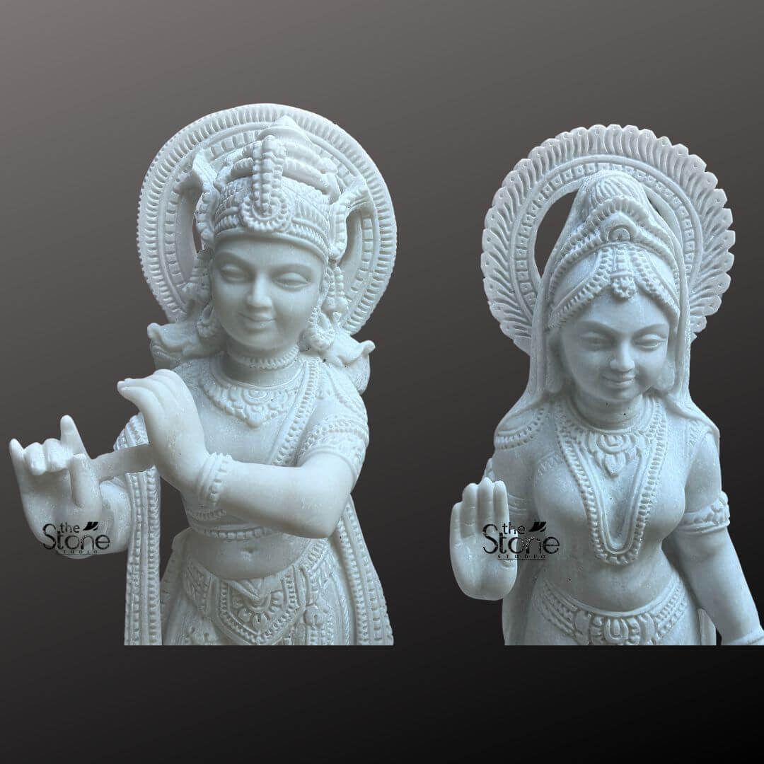 Radha Krishna Marble Stone Statue 3ft 5 This close-up image presents a magnificent Temple Statue of Radha Krishna featuring a pair of 3-foot tall white marble statues. Expertly carved the deities are displayed against a dark neutral background allowing the pristine white marble and intricate details to stand out making them ideal for a temple setting. On the left Lord Krishna is depicted in his iconic Tribhanga posture holding and playing his flute. He is richly adorned with finely sculpted jewelry a detailed crown with a peacock feather and flowing garments all rendered with exceptional precision in the white marble. A prominent intricately carved circular halo is behind his head signifying his divine aura. On the right Radha stands gracefully her right hand raised in a gesture of blessing and her left hand holding a small pot or offering. She is also beautifully adorned with a crown necklaces bracelets and a flowing sari all intricately carved from the same white marble. A similar finely carved circular halo is behind her head. Both statues being white marble statues exude a sense of purity and serenity. The smooth polished surface of the marble reflects light softly emphasizing the delicate features the extensive carvings on their attire and jewelry and the divine expressions of Radha and Krishna. This Temple Statue of Radha Krishna is a beautiful embodiment of sacred love and traditional Indian artistry, perfectly suited for veneration in a temple.