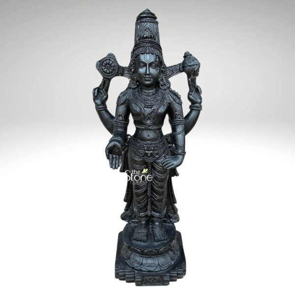 An exquisitely hand-carved 3.5-foot tall Lord Venkateswara Tirupati Balaji Murti, masterfully sculpted from premium natural blackstone, serves as a majestic spiritual centerpiece for a home temple. This large-scale blackstone Balaji statue captures the deity in his iconic standing posture atop a circular lotus pedestal, radiating an aura of divine stability and grace. Lord Venkateswara is portrayed with four arms carrying sacred spiritual symbols: his upper hands hold the Sudarshana Chakra (discus) and the Panchajanya Shankha (conch shell), while his lower left hand rests on his hip in the Kati Hasta pose. The deity is beautifully adorned with a towering tiered crown (Kiritamukuta), layered necklaces, armlets, and a prominent white tilak (Namam) on his forehead, symbolizing divine protection. The craftsmanship highlights incredible detail in the realistic fabric folds of his traditional attire and the intricate patterns of the circular Prabhavali (aura) framing his head. The refined matte charcoal finish of the natural stone emphasizes the heritage of traditional Indian stone masonry, making this 3.5-foot Tirupati Balaji idol a perfect addition to invite peace, prosperity, and spiritual grounding into any residential sanctuary or dedicated prayer space.