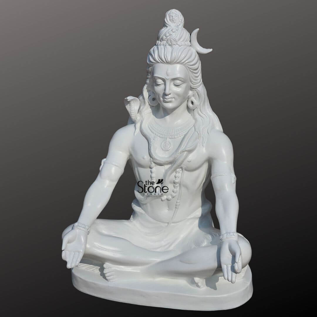 2ft Shiva Meditation Statue 4 A majestic rear view of a 2-foot tall Lord Shiva fibre statue in a pristine white finish showcasing the exceptional 360-degree craftsmanship of this spiritual sculpture. The idol is depicted in a stable meditative seated posture highlighting the intricate detailing of the deity's long, flowing matted hair (Jata) that cascades down his back in rhythmic wavy patterns. A slender white crescent moon is gracefully tucked into the side of his high hair knot providing a subtle yet iconic detail. Crafted from high-quality, durable, and lightweight fibre material this 2ft white Shiva idol offers the elegant appearance of polished marble while being exceptionally weather-resistant. This perspective emphasizes the sculpture’s balanced proportions and realistic textures, making it an ideal spiritual centerpiece for a modern home mandir a personal meditation corner, or an outdoor garden sanctuary designed to invite an aura of peace and divine protection.