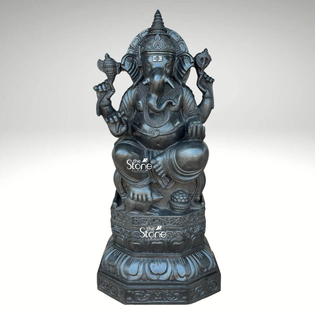 3.5ft Ganesha Garden Statue 1 A magnificent 3.5-foot black stone Ganesha statue sits gracefully showcasing intricate craftsmanship perfect for a garden setting. The deity is depicted in a traditional seated posture on a beautifully carved lotus pedestal which rests upon an octagonal base. Ganesha's elephant head features large ears expressive eyes and a prominent trunk curled towards his left. He is adorned with an elaborate crown necklaces and armlets all meticulously sculpted to highlight the fine details of the black stone. In his upper two hands Ganesha holds a conch shell and an axe while his lower right hand is in a gesture of blessing and his lower left hand holds a bowl of modak. The overall finish of the black stone gives the statue a sophisticated and timeless appearance making it a striking centerpiece for any garden or outdoor space. The statue's substantial size and detailed artistry emphasize its grandeur and spiritual significance aligning perfectly with its description as a 3.5ft Ganesha Garden Statue.