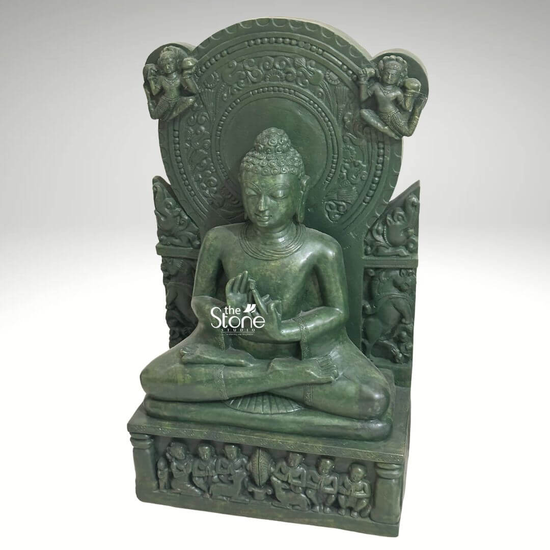 Meditation Buddha Statue 2ft 2 A profoundly serene 2-foot green stone Buddha statue embodying divine calm is presented from a slightly elevated frontal perspective against a plain light background. The statue is carved entirely from green stone giving it a distinctive and earthy hue that evokes ancient artistry. Buddha is depicted in a traditional seated meditation posture with his legs crossed. His hands are positioned in a mudra likely Dharmachakra Mudra or a similar gesture associated with teaching and setting the Wheel of Dharma in motion. His eyes are gently downcast conveying deep introspection and inner peace. His hair is composed of tight uniform curls topped with an ushnisha. The Buddha is seated on a multi-tiered base. The uppermost tier is a simple platform while the lower rectangular pedestal is richly adorned with a frieze of smaller figures possibly disciples or devotees, engaged in worship or listening to teachings. Behind the Buddha's head rises an elaborate, circular prabhavali (halo) with intricate carvings of patterns and possibly celestial beings or motifs. On either side of the prabhavali, winged figures or deities are depicted, adding to the divine aura. The textured surface of the green stone highlights the intricate details of all the carvings, from the delicate features of the Buddha to the elaborate motifs on the backdrop and base. This detailed image powerfully conveys the spiritual majesty and artistic craftsmanship of the green stone Buddha statue, making it highly relevant to an article discussing divine and calm Buddha statues.