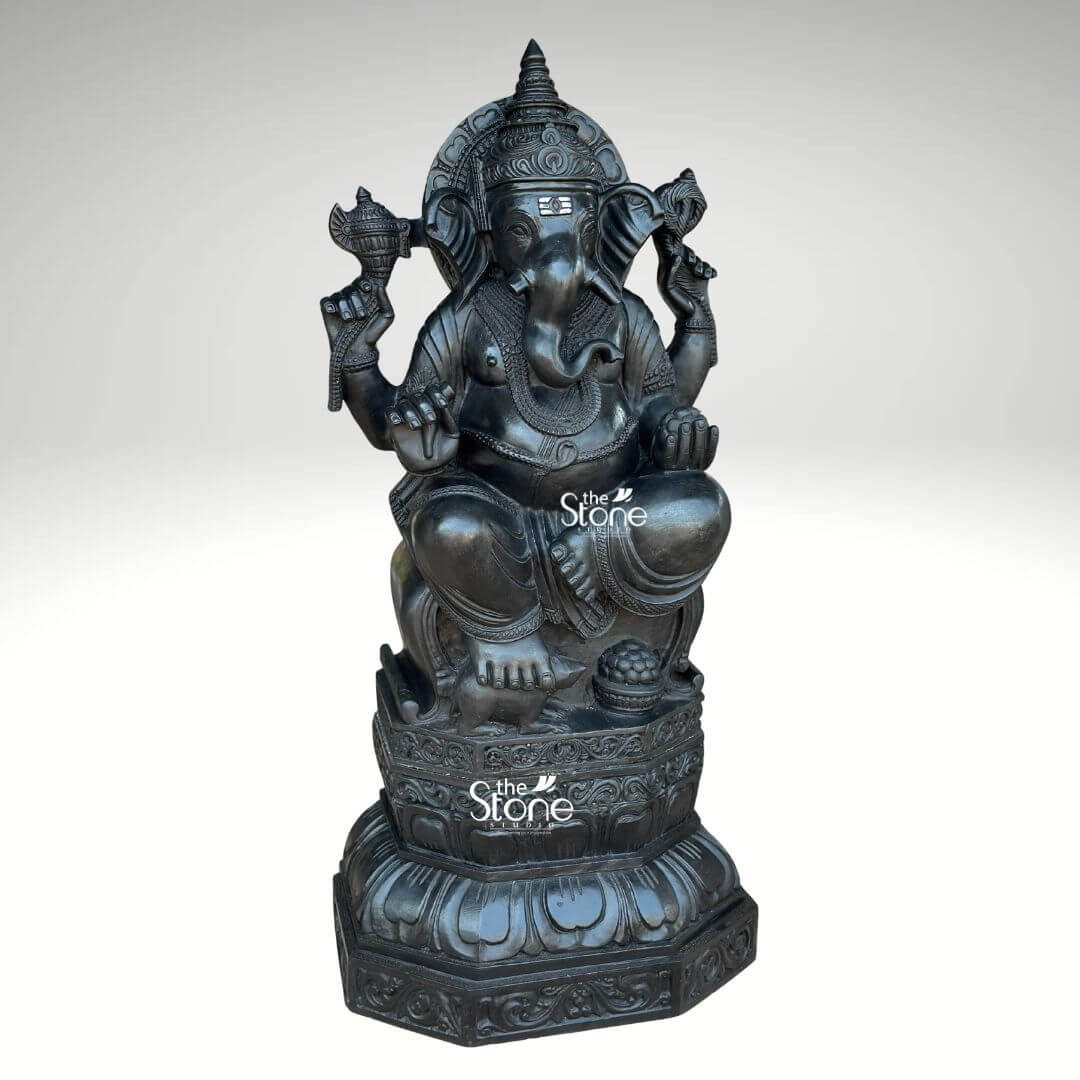3.5ft Ganesha Garden Statue 7 This image showcases a magnificent 3.5-foot black stone Ganpati idol ideal for outdoor display presented against a clear light background that emphasizes its impressive form and detailed craftsmanship. The deity is depicted in a traditional relaxed seated posture embodying an aura of peace, wisdom and strength suitable for an outdoor setting. Ganesha's iconic elephant head is meticulously sculpted featuring large gracefully fanned ears serene, deep-set eyes and a trunk elegantly curled to his left symbolizing auspiciousness and the ability to overcome obstacles. A prominent Tilak mark adorns his forehead, adding to his divine and distinguished countenance. He is richly adorned with an elaborate tiered crown multiple necklaces and finely detailed armlets and anklets all expertly carved to highlight the rich texture and depth of the black stone ensuring durability and beauty outdoors. The large idol is enthroned on a beautifully designed multi-layered lotus pedestal a sacred symbol of purity and spiritual awakening. This pedestal in turn, rests upon a robust octagonal base which is intricately embellished with delicate floral and geometric carvings further enhancing the idol's aesthetic and cultural value. The sturdy construction and material are particularly fitting for an Outdoor Ganpati Idol. Ganesha's four hands each hold significant attributes: his upper right hand grasps a conch shell, and his upper left an axe representing divine sound and the power to remove impediments. His lower right hand is raised in a gesture of blessing offering grace and protection, while his lower left hand cradles a bowl of modak, his favorite sweet, symbolizing the sweet fruits of devotion and knowledge. The smooth dark finish of the black stone imparts a timeless elegance and powerful presence to this substantial Ganesha idol making it a focal point capable of withstanding outdoor elements while maintaining its artistic integrity. Every curve and contour from the folds of his dhoti to the delicate details of his jewelry is rendered with exceptional craftsmanship designed to bring beauty and spiritual energy to any outdoor space. This detailed alt text comprehensively describes the idol's visual elements emphasizing its suitability and connection to the article's focus on a durable and aesthetically rich outdoor Ganesha sculpture.