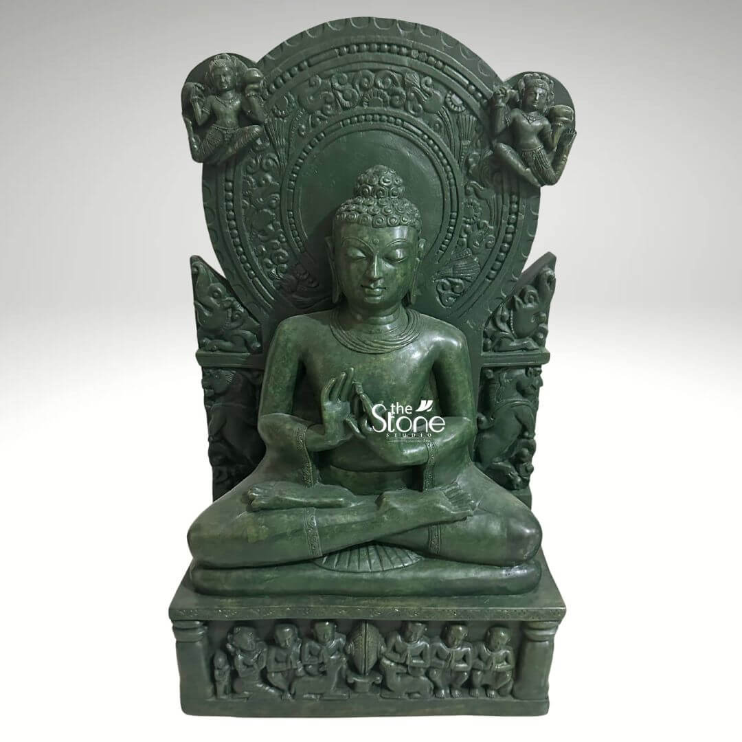 Meditation Buddha Statue 2ft 4 An exquisitely hand-carved 2-foot tall peaceful Buddha throne statue masterfully sculpted from a single block of natural green stone. This spiritual centerpiece depicts Lord Buddha in a serene seated meditative pose with his hands held in the Dharmachakra Mudra symbolizing the transmission of wisdom and the turning of the wheel of dharma. The deity is positioned atop a multi-tiered, rectangular throne base adorned with high-relief carvings of several small seated figures representing disciples in devotion. Framing the Buddha is a grand and highly intricate Prabhavali showcasing rhythmic floral patterns and traditional stone-carved motifs. In the upper corners of this decorative backplate, two celestial beings are delicately rendered in relief. The deep emerald green tones and polished texture of the natural stone highlight the exceptional artisan craftsmanship, from the Buddha's tranquil facial expression and closed eyes to the traditional ushnisha hair and elongated earlobes. Designed for both durability and aesthetic grace, this green stone Buddha statue serves as a profound spiritual focal point for a home mandir, garden landscape, or meditation sanctuary, inviting an atmosphere of deep peace, stability, and mindfulness into the environment.