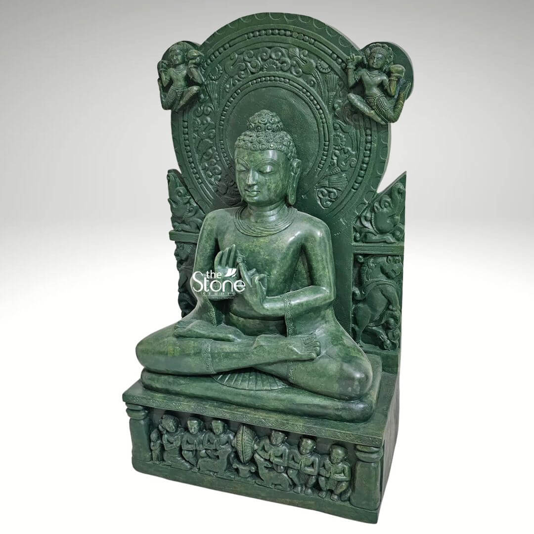Meditation Buddha Statue 2ft 6 An exquisite 2-foot tall Lord Buddha serenity meditation statue masterfully hand-carved from natural green stone. Shown from a three-quarter side angle to emphasize its depth and volume this spiritual centerpiece depicts Lord Buddha in a state of deep contemplation seated in the traditional cross-legged Padmasana atop an intricate multi-tiered rectangular pedestal. The deity's right hand is raised in the Vitarka Mudra symbolizing the transmission of wisdom and the turning of the wheel of dharma. The sculpture is magnificently framed by a grand and highly detailed Prabhavali showcasing circular halo motifs directly behind the head and two celestial figures delicately rendered in the upper corners. The base of the green stone Buddha statue features high-relief carvings of several small seated figures representing disciples in devotion. The deep emerald green tones and refined polished finish of the natural stone highlight the exceptional artisan craftsmanship from the Buddha's tranquil facial expression and closed meditative eyes to the traditional ushnisha hair and realistic anatomical details. This durable and weather-resistant 2ft stone sculpture serves as a profound focal point for a home mandir Zen garden, or meditation sanctuary, designed to invite an aura of peace spiritual stability and mindfulness into the surroundings.
