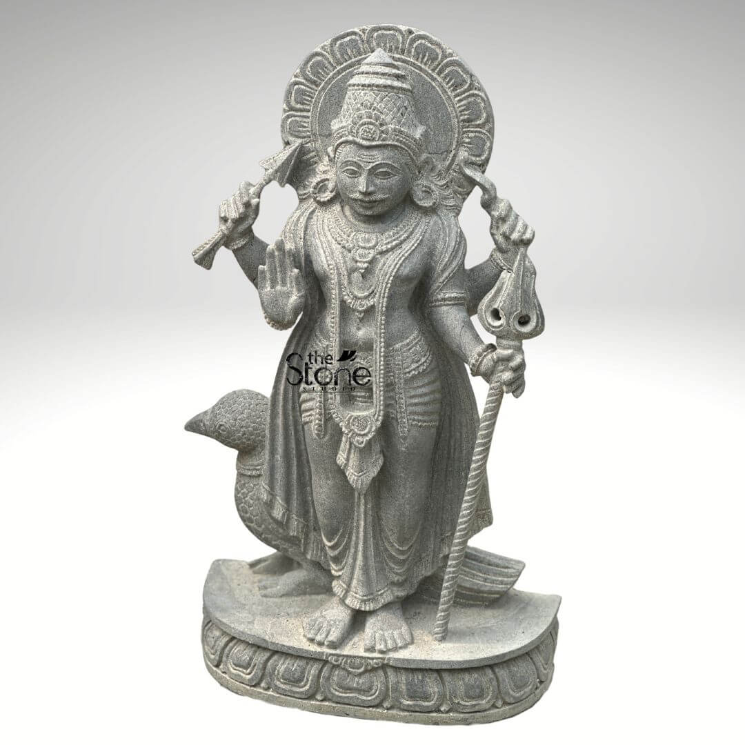 Shani Dev Stone Statue with Crow 27" 6 An exquisitely hand-carved 27-inch Shani Dev stone sculpture masterfully sculpted from premium natural blackstone with a refined rustic matte finish. The deity, known as the lord of justice and the planet Saturn, is depicted in a majestic standing posture atop an intricately carved Lotus pedestal. Lord Shani is portrayed with four arms carrying sacred spiritual symbols: his upper hands hold a traditional bow and arrow, while his lower right hand is raised in the Abhaya Mudra the universal gesture of protection and fearlessness. His lower left hand rests firmly on an ornate staff or Gada. Standing faithfully behind his right leg is the crow, his divine vehicle or vahana, carved with lifelike precision to complete the authentic spiritual iconography. The craftsmanship showcases incredible detail, from the towering, tiered mukut (crown) and expressive facial features to the intricate layered necklaces and the realistic, fluid folds of his traditional attire. Framing the head is a grand, circular Prabhavali embellished with rhythmic relief patterns that represent a divine halo. The deep charcoal-grey tones and grainy texture of the stone highlight the heritage of traditional Indian stone masonry making this Shani Dev statue an ideal spiritual centerpiece for a home mandir, garden sanctuary, or personal altar, designed to invite discipline, stability, and divine protection into any environment.