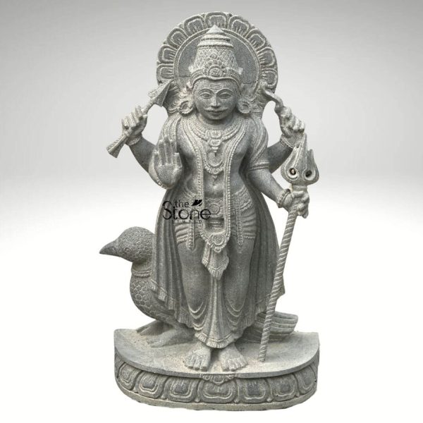 An exquisitely hand-carved 27-inch Shani Dev stone statue masterfully sculpted from premium natural blackstone with a refined, rustic matte finish. The deity, known as the Lord of Justice and the planet Saturn, is depicted in a majestic standing posture atop a circular lotus pedestal. Lord Shani is portrayed with four arms holding sacred spiritual symbols: his upper hands hold a traditional bow and arrow, while his lower right hand is raised in the Abhaya Mudra the universal gesture of protection and fearlessness. His lower left hand rests firmly on an ornate Trishula staff. Standing faithfully behind his feet is the crow his divine vehicle or vahana, carved with lifelike precision to complete the authentic spiritual iconography. The craftsmanship highlights incredible detail, from the towering, tiered mukut and expressive facial features to the intricate layered necklaces and the realistic, fluid folds of his traditional dhoti. Framing the head is a grand, circular Prabhavali (ornate arch) embellished with rhythmic relief patterns that represent a divine halo. The deep charcoal-grey tones and grainy texture of the stone emphasize the heritage of traditional Indian stone masonry making this blackstone Shani Dev idol an ideal spiritual centerpiece for a home mandir, garden sanctuary, or personal altar, designed to invite discipline, stability, and divine protection into any environment.