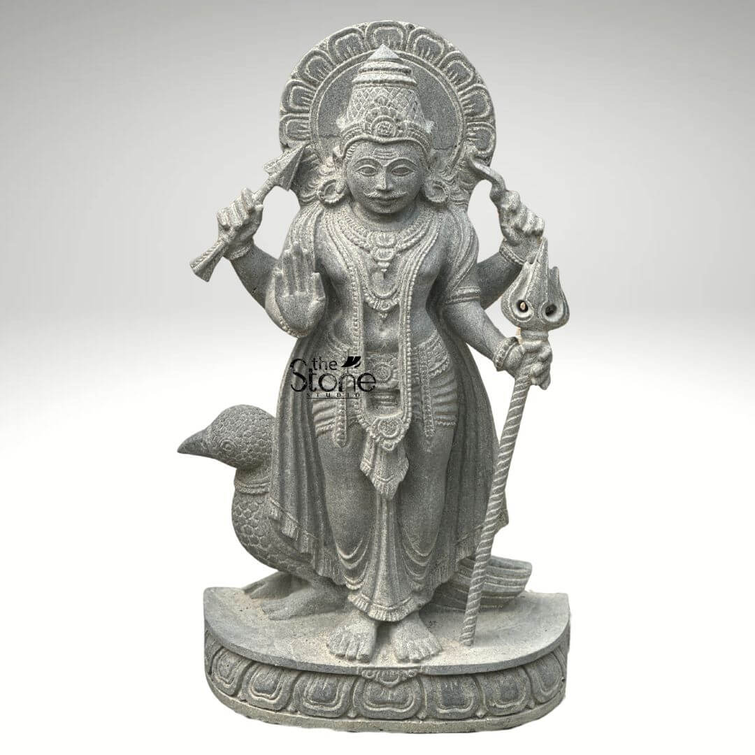 Shani Dev Stone Statue with Crow 27" 1 An exquisitely hand-carved 27-inch Shani Dev stone statue masterfully sculpted from premium natural blackstone with a refined, rustic matte finish. The deity, known as the Lord of Justice and the planet Saturn, is depicted in a majestic standing posture atop a circular lotus pedestal. Lord Shani is portrayed with four arms holding sacred spiritual symbols: his upper hands hold a traditional bow and arrow, while his lower right hand is raised in the Abhaya Mudra the universal gesture of protection and fearlessness. His lower left hand rests firmly on an ornate Trishula staff. Standing faithfully behind his feet is the crow his divine vehicle or vahana, carved with lifelike precision to complete the authentic spiritual iconography. The craftsmanship highlights incredible detail, from the towering, tiered mukut and expressive facial features to the intricate layered necklaces and the realistic, fluid folds of his traditional dhoti. Framing the head is a grand, circular Prabhavali (ornate arch) embellished with rhythmic relief patterns that represent a divine halo. The deep charcoal-grey tones and grainy texture of the stone emphasize the heritage of traditional Indian stone masonry making this blackstone Shani Dev idol an ideal spiritual centerpiece for a home mandir, garden sanctuary, or personal altar, designed to invite discipline, stability, and divine protection into any environment.