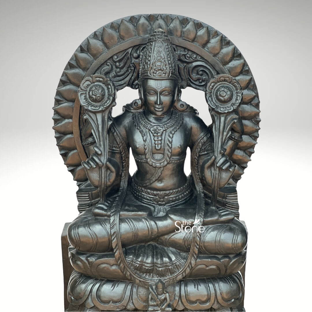Surya Dev Black Stone Statue 30" 6 A majestic 2.5-feet black stone Surya Bhagwan statue is presented from a frontal slightly elevated perspective against a plain light background. The sculpture depicts Surya Dev the Hindu solar deity, seated in a regal posture, embodying power and enlightenment. The entire statue is meticulously carved from rich dark black stone which gives it a profound and traditional presence, with a subtle antique-like sheen. Surya Dev is shown with two arms each holding a blooming lotus flower symbols of purity and creation extending upwards from his shoulders. He is richly adorned with an elaborate crown intricate necklaces armlets, earrings, and a sacred thread across his chest. His serene face, with slightly downcast eyes radiates benevolence. Behind his head rises a grand, circular prabhavali intricately carved with multiple layers of lotus petals radiating outwards, symbolizing the sun's rays and his divine effulgence. The base of the statue is a multi-tiered lotus throne, beneath which a small, subtle figure, possibly a devotee or the charioteer Aruna, is partially visible at the very bottom. The smooth yet detailed finish of the black stone highlights the fine artistry and the powerful, benevolent presence of the solar deity. This detailed image powerfully conveys the spiritual majesty and artistic craftsmanship of the black stone Surya Dev statue, making it highly relevant to an article discussing such revered idols.