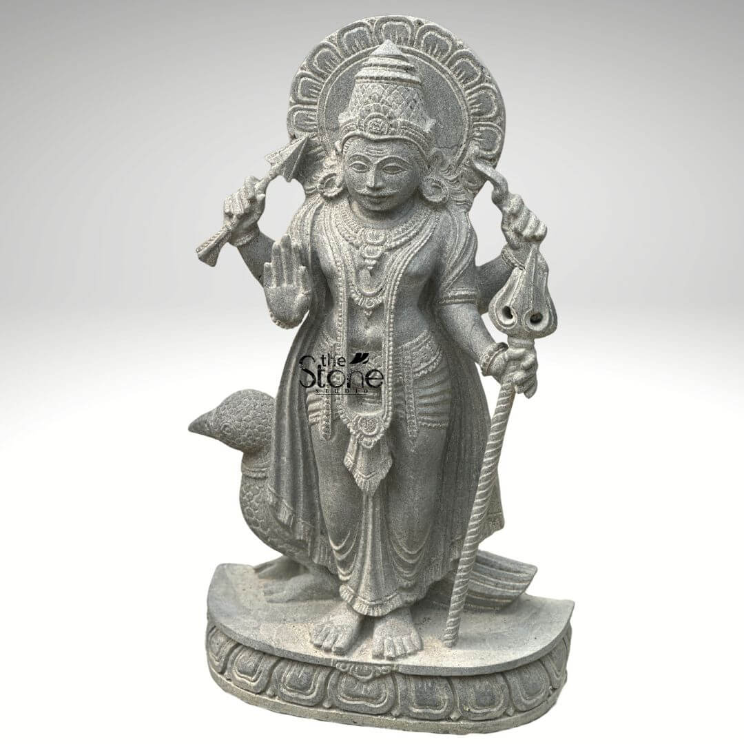 Shani Dev Stone Statue with Crow 27" 7 An exquisitely hand-carved 27-inch traditional Shani Dev stone idol masterfully sculpted from premium natural blackstone with a refined rustic matte finish. This spiritual masterpiece depicts Shani Dev the lord of justice and the planet Saturn in a majestic standing posture atop a circular, tiered lotus pedestal. The deity is portrayed with four arms carrying sacred spiritual symbols: his upper hands hold a traditional bow and arrow, while his lower right hand is raised in the Abhaya Mudra the universal gesture of protection and fearlessness. His lower left hand rests firmly on a long, ornate Trishula or staff. Standing faithfully behind his right leg is the crow, his divine vehicle or vahana, carved with lifelike precision to complete the authentic spiritual iconography. The craftsmanship highlights incredible detail from the towering, tiered mukut (crown) and expressive facial features to the intricate layered necklaces and the realistic, fluid folds of his traditional dhoti. Framing the head is a grand, circular Prabhavali embellished with rhythmic relief patterns that represent a divine aura. The deep charcoal-grey tones and grainy texture of the stone emphasize the heritage of traditional Indian stone masonry making this blackstone Shani Dev statue an ideal spiritual centerpiece for a home mandir, garden sanctuary, or personal altar, designed to invite discipline, stability, and divine protection into any environment.