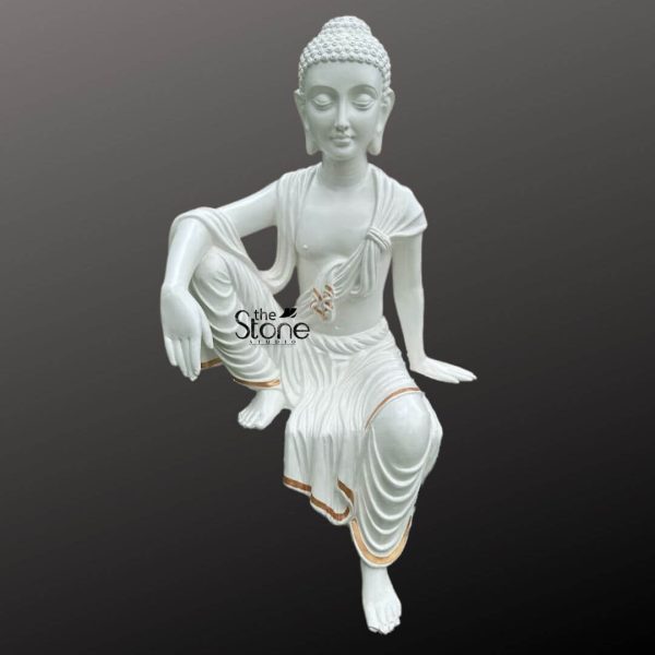 A serene 3.5-feet fiber white Sitting Buddha Garden Statue is presented from a slightly elevated frontal perspective set against a dark unadorned background. The statue depicts Buddha in a contemplative and relaxed seated posture with one leg bent and drawn closer to the body and the other extending forward. His hands rest gently on his knees or beside him palms open in a gesture associated with teaching or meditation. The Buddha's face exudes tranquility with downcast eyes and a subtle smile embodying inner peace. His hair is composed of tight uniform curls topped with a ushnisha (topknot) symbolizing heightened spiritual awareness. The white fiber material of the statue is accented with thin golden lines along the edges of his flowing robes adding a touch of elegance. A subtle symbol, possibly a swastika or similar auspicious mark is visible on the drapery near his waist. The drapery of the robes is intricately sculpted showcasing soft folds and movement. This detailed image emphasizes the tranquil beauty and spiritual presence of the large fiber white sitting Buddha statue making it an ideal visual for an article about garden statues.