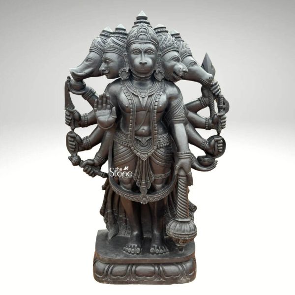 A magnificent 5-foot tall Panchamukhi Hanuman statue meticulously carved from black stone stands majestically embodying immense power and divine protection. This five-faced form of Lord Hanuman features his central monkey face flanked by four other divine faces Hayagriva (horse) Narasimha (lion-man), Garuda (eagle) and Varaha (boar) each intricately detailed and representing different aspects of his strength and blessings. His central face wears a serene yet resolute expression adorned with a crown and traditional jewelry including necklaces and armlets. Lord Hanuman is depicted standing firmly on a lotus base with his multiple arms radiating outwards each holding various sacred weapons and attributes such as a bow and arrow a trident, a mace and other implements. One of his central hands is raised in the Abhaya Mudra. The intricate carvings extend to his traditional attire flowing sash and powerful physique highlighting the fine artistry and the natural texture of the black stone. The dark polished surface of the stone lends a formidable and timeless quality to the sculpture. The robust base of the statue features traditional Indian design motifs providing a stable and aesthetically pleasing foundation. Presented against a plain light grey background the majestic height and intricate details of the Panchamukhi Hanuman statue are beautifully accentuated. Its impressive 5-foot stature ensures it makes a commanding and deeply spiritual presence ideal for a temple a grand interior space or a prominent outdoor setting serving as a powerful symbol of courage devotion and protection from all directions.