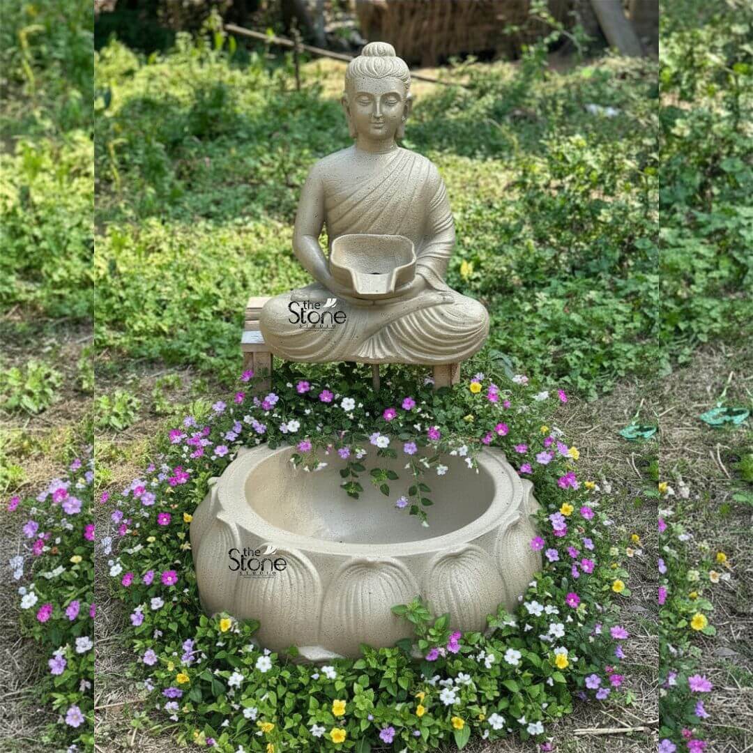 Wall-Mounted Buddha Fountain 3ft 3 A serene Buddha fountain statue crafted from fiber with a warm sandy tone is charmingly installed outdoors against a backdrop of natural greenery evoking a tranquil garden setting. This wall-mounted style fountain features a peaceful Buddha figure seated in the lotus position on a rustic wood-like platform creating a harmonious blend of spiritual art and natural elements. The Buddha's hands are gently placed in his lap holding a small shallow bowl from which water is designed to flow. His eyes are downcast conveying a deep sense of meditation inner peace and spiritual tranquility. The Buddha statue exhibits smooth flowing robes draped elegantly over his body with visible folds that add texture and realism. His facial features are serene and finely sculpted featuring a prominent ushnisha on his head symbolizing wisdom and elongated earlobes indicative of his renunciation of worldly possessions. The fiber material rendered in an earthy light brown hue gives the statue a natural weathered look that blends seamlessly with the garden environment. Below the Buddha figure a large, intricately carved lotus-shaped basin collects the water. This basin matching the sandy tone of the Buddha features multiple layers of detailed lotus petals symbolizing purity and spiritual awakening. The design suggests that water gracefully cascades from the Buddha's bowl into this larger basin. The entire fountain is surrounded by a vibrant array of small colorful flowers in shades of purple white, and yellow along with lush green foliage, which creates a natural, living frame around the water feature. The background consists of soft, blurred green grass and foliage emphasizing the peaceful outdoor setting. This Buddha fountain with its calming presence and natural aesthetic is an ideal addition to any garden or outdoor spiritual space, as highlighted in an article discussing wall-mounted Buddha fountain statues.