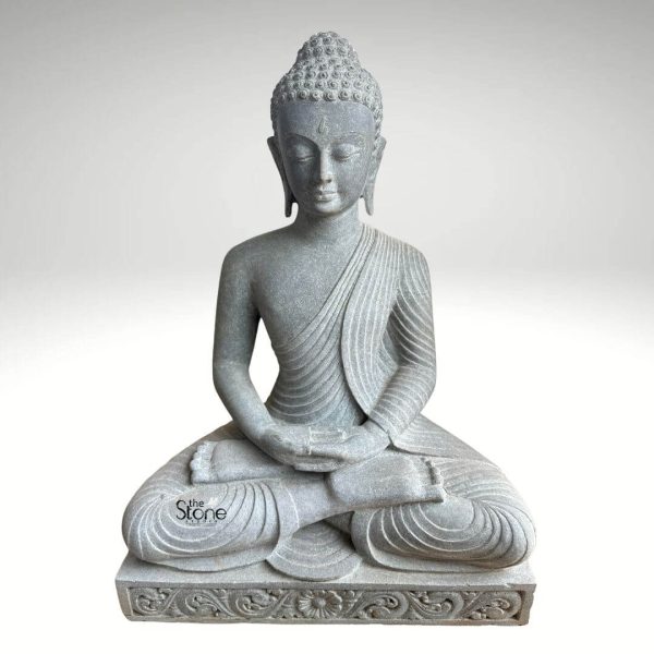 A serene 2.5-foot tall Buddha statue meticulously carved from black stone sits in a classic meditative posture ideal for a terrace garden. The Buddha's hands rest gently in his lap in the Dhyana Mudra conveying profound peace and concentration. His eyes are softly closed and his expression is tranquil with finely detailed features including his tightly coiled hair elongated earlobes and subtle smile. The flowing robes are intricately sculpted with graceful folds creating a sense of natural drapery. The statue is positioned on a decorative rectangular base which is adorned with intricate floral or traditional scrollwork carvings along its edges. The textured surface of the black stone lends a natural earthy quality to the sculpture making it blend harmoniously with an outdoor garden environment while providing a dignified presence. The inherent durability of black stone ensures it can withstand outdoor elements making it perfectly suited for a terrace garden. Presented against a plain light grey background the texture and intricate details of the black stone statue are beautifully highlighted. Its compact yet significant size at 2.5 feet makes it a perfect focal point for a smaller outdoor space like a terrace bringing an aura of tranquility mindfulness and spiritual serenity to the area. This Buddha statue serves as both a beautiful artistic element and a powerful symbol of enlightenment and inner peace.