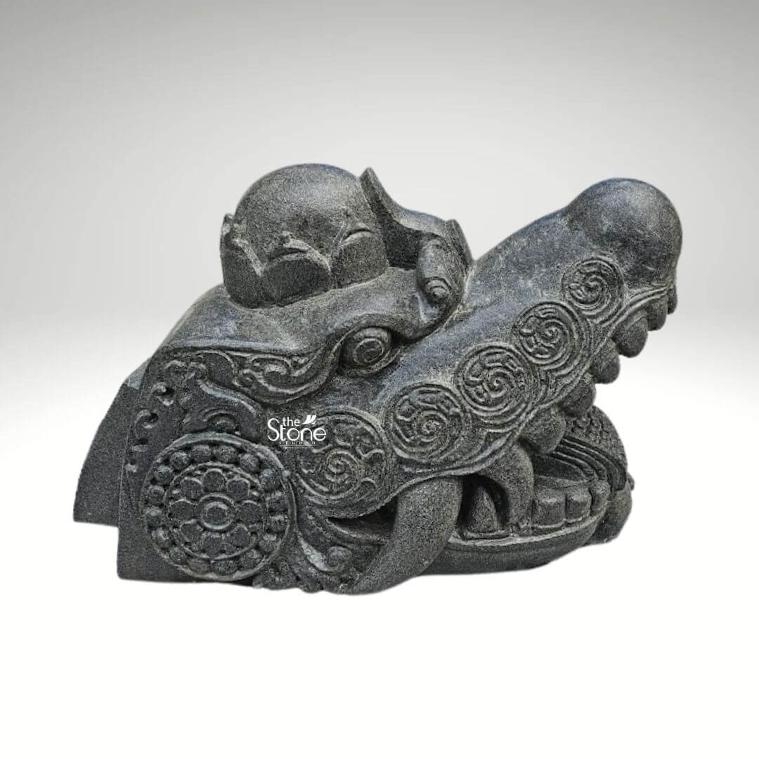 Dragon Head Statue 18" 1 A striking black stone dragon head statue measuring 1.5 feet in depth and 1 foot in height is presented against a plain background highlighting its intricate carvings and formidable presence. The sculpture captures the fierce and mystical essence of a dragon with its powerful snout and open mouth revealing menacing fangs. The texture of the black stone with its natural variations and subtle sheen enhances the ancient and weathered appearance of the mythical creature. The dragon's head is adorned with elaborate swirling patterns carved into the stone characteristic of traditional Asian dragon iconography. Circular motifs resembling ancient coins or floral designs are intricately integrated into the broader decorative scheme adding a layer of cultural depth to the piece. The eyes though stylized convey an intense gaze while the brow is furrowed suggesting a creature of immense power and wisdom. On the top of the head a small crown-like protrusion or perhaps a horn is visible further emphasizing its regal and mythical status. The craftsmanship is evident in the finely detailed scales and ridged textures that delineate the dragon's features from its snout to the back of its head. The contours are smooth in some areas and rugged in others, creating a dynamic interplay of light and shadow that accentuates the three-dimensional form. This blackstone dragon head statue is not merely a decorative item but a piece of art that embodies strength protection, and ancient folklore making it an ideal subject for an article discussing such unique and culturally rich sculptures. Its size and material suggest it could be a significant architectural element, a garden ornament or a substantial display piece in a collection.