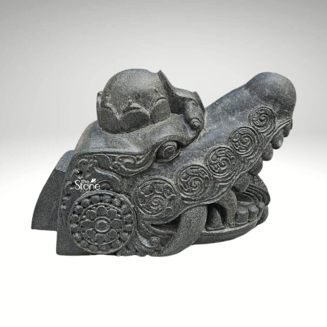 Dragon Head Statue 18" 2 A formidable black stone dragon head statue measuring 1.5 feet in length and 1 foot in height is showcased against a clean neutral background emphasizing its intricate details and commanding presence. This sculpture is specifically designed as a decorative or protective element for an entrance embodying the power and mystique associated with dragons. The dragon's head features a robust snout with an open mouth revealing sharp stylized fangs that convey a sense of vigilance and strength. The dark textured black stone gives the piece an ancient and enduring quality suitable for an outdoor or prominent architectural placement. The surface of the dragon's head is richly adorned with traditional flowing carved patterns including swirling motifs that suggest scales or mystical energy. Intricate circular designs reminiscent of ancient symbols or stylized flowers are integrated into the overall ornamentation adding to its cultural authenticity. The eyes are deeply set and carved with a focused gaze enhancing the protective aura of the dragon. A subtle crown-like or horn-like protrusion on the top of the head further establishes its majestic and mythical status. The craftsmanship highlights varying textures from smoother contours on the brow to more rugged scale-like details along the jawline and neck. These textural variations create a dynamic interplay of light and shadow giving the sculpture a lifelike quality despite its stone medium. This blackstone dragon head statue is not merely an artistic embellishment but a symbolic guardian perfectly suited for an entrance where it can evoke a sense of grandeur, tradition and protection aligning well with an article about dragon heads designed for architectural features.