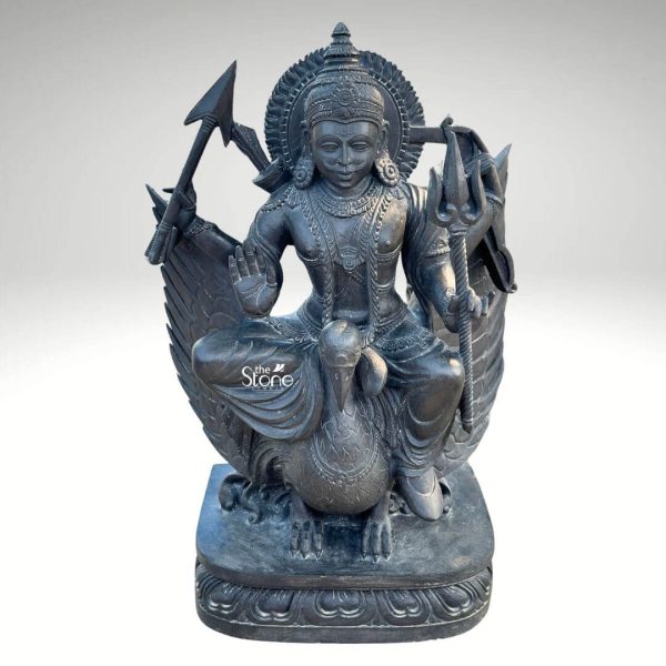 A powerful 3.5-foot tall statue of Lord Shani Dev meticulously carved from black stone is depicted seated majestically on his vahana a crow. The deity is shown with a serene yet commanding expression adorned with traditional jewelry and a crown emanating an aura of divine authority. In his hands Lord Shani holds his characteristic attributes a trident in one and an arrow in another with a bow subtly suggested behind him symbolizing justice discipline and karmic retribution. A halo or prabhavali with radiating lines frames his head signifying his divine radiance and power. The intricate details of the carving are apparent in the crow's textured feathers and robust form as well as in the deity's elaborate garments and the subtle contours of his figure. The black stone material lends a formidable and timeless quality to the statue emphasizing the gravitas associated with Lord Shani. The base of the statue is robust featuring traditional Indian design motifs providing a stable and aesthetically pleasing foundation. The statue is presented against a plain light grey background which allows the deep dark hue and intricate details of the black stone to stand out prominently. This depiction of Lord Shani Dev with his crow vahana is culturally significant representing cosmic law and the effects of one's actions making it an ideal focal point for worship and contemplation in temples or dedicated altars. The impressive height and detailed craftsmanship convey the reverence and importance of this powerful deity.