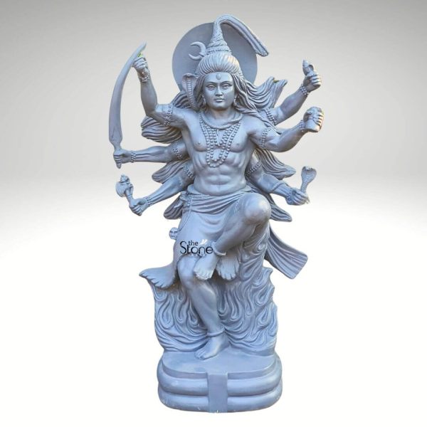 A dynamic and powerful Shiva Tandava statue crafted from fiber-reinforced plastic (FRP) with a grey stone-like finish depicts Lord Shiva in his cosmic dance. This multi-armed deity is shown with his right leg raised in a vigorous dancing pose symbolizing the rhythm of creation and destruction. Lord Shiva's muscular physique is prominently displayed adorned with traditional jewelry including necklaces armlets and anklets. A cobra is intricately sculpted around his neck and a crescent moon crowns his elaborate flowing hair which extends outwards suggesting movement. Shiva's face bears a intense yet serene expression with eyes open conveying both divine power and profound detachment. He has multiple arms each holding various symbolic attributes: a sword, a trident a drum and an axe along with gestures of fearlessness and creation. The lower part of the statue is designed to resemble stylized flames emanating from his dancing form reinforcing the destructive and regenerative aspects of the Tandava dance. The entire sculpture is mounted on a sturdy multi-tiered rectangular base providing stability for the dynamic pose. Presented against a plain light grey background the intricate details and powerful movement of the Shiva Tandava statue are strikingly highlighted. This FRP sculpture captures the raw energy and spiritual significance of Lord Shiva's cosmic dance making it an impressive and compelling piece for a temple a grand interior space or a specialized spiritual decor collection.
