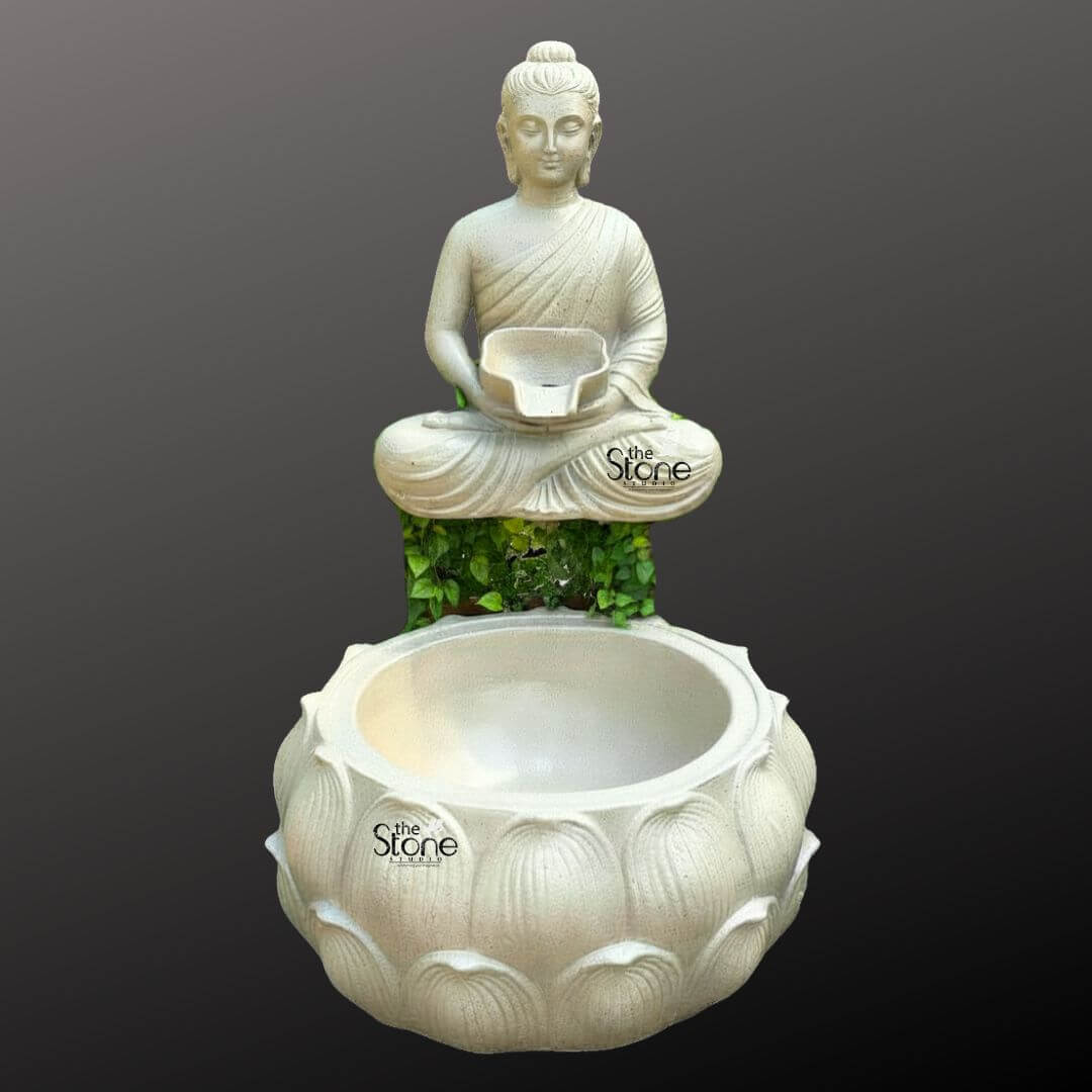 Wall-Mounted Buddha Fountain 3ft 1 A serene wall-mounted Buddha fountain crafted from fiber and designed to create a peaceful water feature is presented against a dark featureless background highlighting its elegant form. The fountain features a tranquil Buddha figure seated in the lotus position atop a textured green-foliage-like base which implies natural growth or moss. The Buddha's posture is one of deep meditation with hands gently placed in his lap holding a small bowl from which water would gently flow. His eyes are downcast conveying a sense of inner peace and contemplation. The Buddha statue rendered in a light off-white or cream color exhibits smooth flowing robes draped elegantly over his body. His facial features are serene and finely sculpted with a ushnisha on his head symbolizing wisdom and elongated earlobes indicative of his renunciation of worldly possessions. The fiber material allows for a detailed and lightweight construction making it suitable for wall mounting. Below the Buddha figure a large, intricately carved lotus shaped basin collects the water. The basin is also in a similar light color and features multiple layers of detailed lotus petals symbolizing purity and spiritual awakening. The design suggests that water would cascade from the Buddha's bowl into this larger basin, creating a gentle soothing sound. The green foliage beneath the Buddha statue visually connects the upper and lower parts of the fountain adding an organic touch. This Buddha fountain is an ideal piece for creating a calming and meditative atmosphere in a garden, patio or indoor spiritual space as suggested by its use in an article about wall-mounted Buddha fountains.