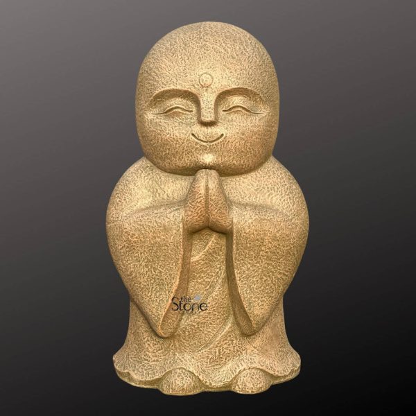 A charming 3-foot Praying Monk Fibre Statue crafted from a textured earthy-toned fibre stands serenely against a plain dark background highlighting its calming presence. This 3 Feet Fibre Monk Statue depicts a young monk with a round bald head eyes gently closed and a subtle blissful smile on his face radiating peace and contentment. His hands are pressed together in the traditional Añjali Mudra at his chest embodying humility reverence and spiritual connection perfectly representing a 3ft Praying Monk Fibre Statue. The surface of the statue features a slightly rough stone-like texture giving it an organic and grounded feel despite being made of fibre. The monk is simply robed with the folds of his garment subtly suggested by the sculpture's form emphasizing the simplicity and focus on spiritual devotion. The details are minimalist yet expressive conveying a sense of inner tranquility that makes the statue an ideal addition to any space seeking a calm ambiance. The light beige or light brown color of the fibre ensures it blends harmoniously with various decor styles from modern minimalist to more traditional settings. The overall form is robust and stable hinting at its suitability for both indoor and outdoor placement. The statue's presence is one of quiet contemplation and warmth inviting viewers to share in its peaceful demeanor. Its substantial 3-foot height makes it a noticeable focal point without being overwhelming suitable for a meditation corner garden or entryway. This detailed description effectively connects the visual elements of the 3 Feet Fibre Monk Statue with its spiritual message and aesthetic appeal, making it an ideal representation for an article about a 3ft Praying Monk Fibre Statue.