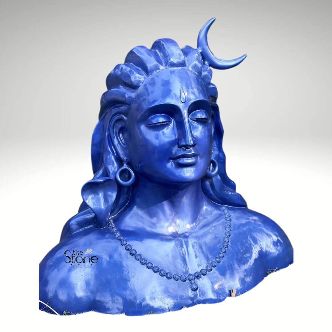 Blue Adiyogi Shiva Statue 4ft 7 A striking 4-foot fiber statue of the Blue Adiyogi Shiva bust is prominently displayed against a plain background making it an evocative piece for home decor. The sculpture captures the upper torso and head of Lord Shiva in his Adiyogi form depicted with closed eyes in deep meditation conveying profound inner peace and wisdom. His iconic third eye is subtly marked on his forehead and a prominent crescent moon gracefully adorns his matted locks which are styled upwards and flow around his shoulders symbolizing his ascetic nature. The entire statue is rendered in a vibrant deep blue color characteristic of Shiva's divine complexion which would serve as a captivating focal point in any room. Shiva's ears are adorned with traditional large ring earrings and a detailed serpent is subtly carved around his neck along with a beaded necklace adding to his divine iconography. The intricate detailing on his hair ornaments and facial features showcases remarkable artistry. The smooth glossy finish of the fiber material enhances the statue's vibrant blue hue making it a visually captivating piece that evokes both ancient reverence and modern artistic interpretation. The robust fiber construction ensures the statue is durable yet relatively lightweight suitable for various indoor and outdoor settings within a home. The statue's bust-like form with its broad shoulders and serene countenance exudes a powerful yet tranquil presence making it a compelling addition to any room or garden. This 4-foot fiber Blue Adiyogi Shiva statue truly embodies spiritual power and artistic grace with its intense blue color adding to its mystique. Its commanding yet peaceful presence makes it a powerful symbol of yoga and ultimate liberation, perfect for inspiring contemplation and reverence in a home environment.