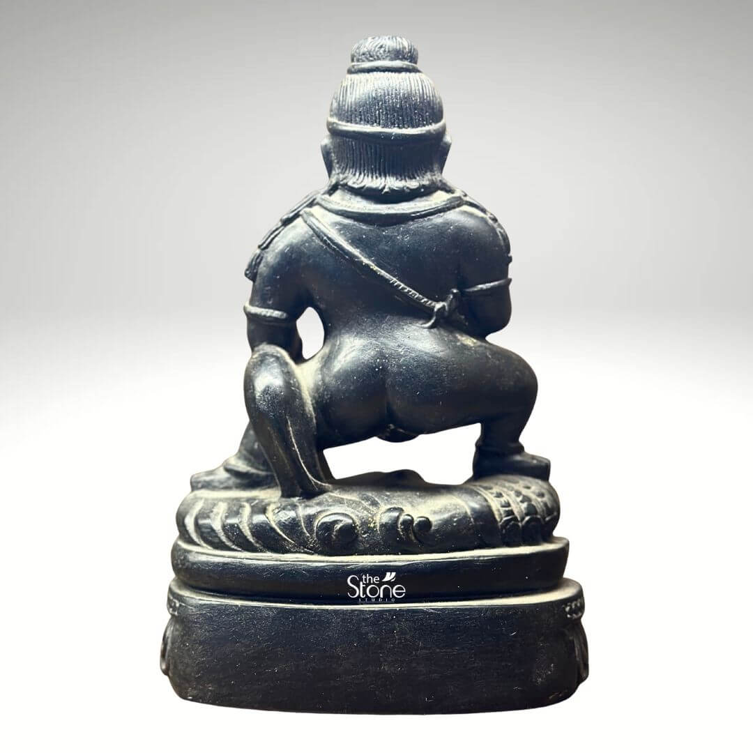 Black Stone Jambhala Statue 9" 6 This image provides a rear view of the 9-inch Buddhist Wealth God Jambhala statue meticulously carved from black stone set against a neutral background. The perspective highlights the robust and dynamic squatting posture of the deity showcasing the sculptor's skill in rendering the figure's three-dimensionality. The dark polished black stone emphasizes the strong muscular curves of Jambhala's back buttocks, and legs conveying a sense of immense power and solidity. This rear angle reveals the depth and mass of the sculpture complementing the details seen from the front. From this view details such as the intricate patterns of the headdress the drape of garments or sashes over the shoulders and the general outline of the arms are visible even if the specific attributes held in the hands are not. The robust form of the deity's legs firmly planted on the base underscores his stability and grounded nature as a bestower of wealth. The back of the intricately carved lotus pedestal is also clearly visible showing its layered design and reinforcing the sacred symbolism of the foundation. The texture and natural variations in the black stone are evident across the entire surface. As an image used in an article about the Buddhist Wealth God Jambhala statue this rear view is crucial for illustrating the complete craftsmanship of the 9-inch black stone idol. It allows collectors and enthusiasts to appreciate the full extent of the carving and the quality of the material from all angles. This perspective reinforces the statue's substantial presence and artistic integrity underscoring its value as a powerful and well-executed representation of Jambhala the deity associated with prosperity and protection in Buddhist tradition.