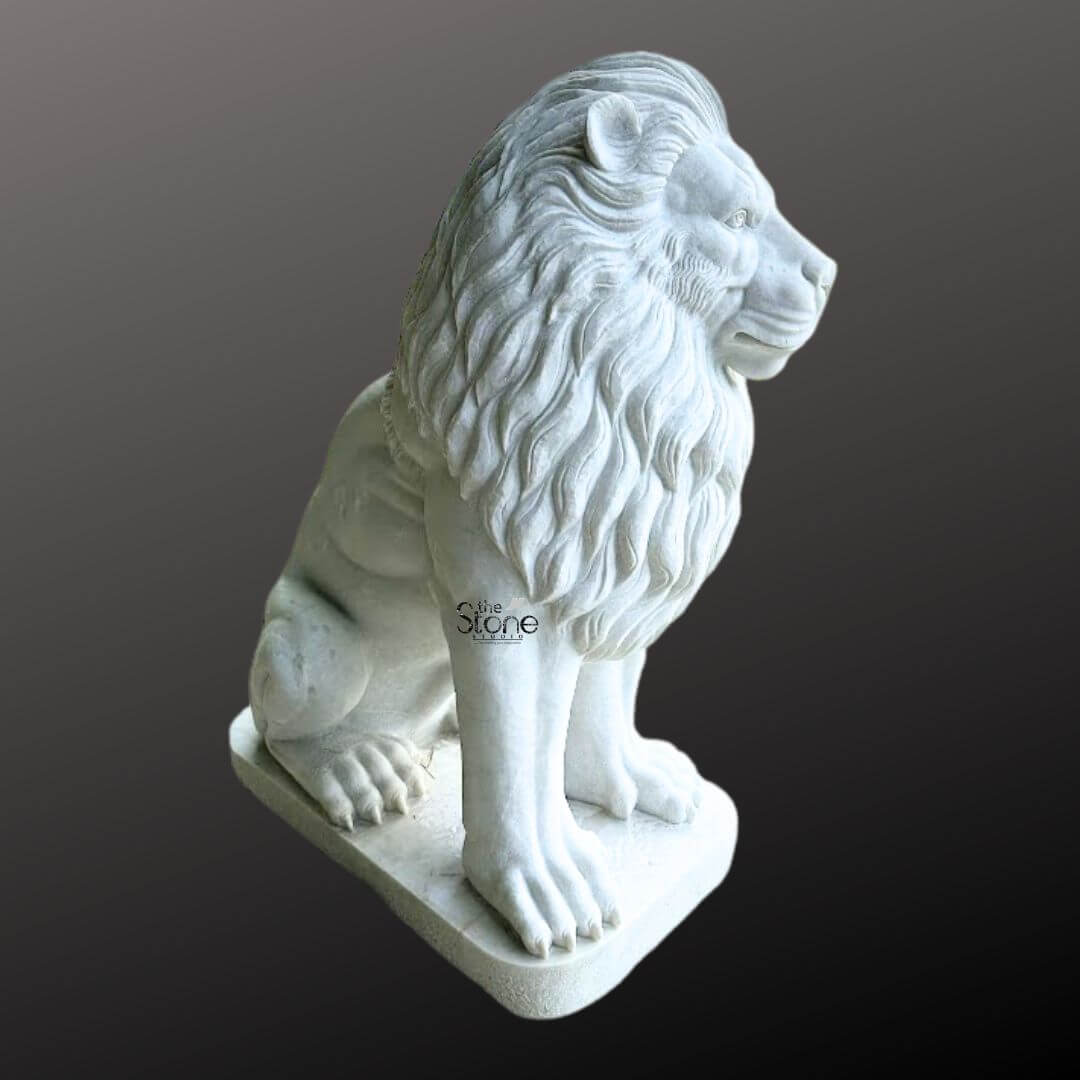 White Marble Lion Statue 5ft 4 A magnificent lion statue meticulously carved from white marble is prominently displayed in a side profile against a dark gradient background serving as a prime example for an article on lion statues in white marble. The lion is sculpted in a regal seated position with its powerful body held upright and its head turned to the right gazing intently into the distance. Its profile reveals a detailed and majestic expression with a strong jawline defined eyes and a prominent nose. The intricate carving brilliantly captures the texture of its flowing voluminous mane which cascades around its head neck and shoulders conveying a sense of immense power and dignity. The statue is crafted from pristine white marble which exquisitely emphasizes the fine details of the carving from the individual strands within the mane to the robust structure of its paws and the sharp definition of its claws. The smooth polished surface of the marble subtly reflects ambient light accentuating the contours and musculature of the lion's form. The inherent beauty and purity of the white marble are showcased highlighting the exceptional skill of the artisan in bringing such a formidable creature to life in stone. The white marble lion statue rests on a sturdy rectangular base also carved from matching white marble providing a solid foundation and integrating seamlessly with the overall design. This elegant sculpture captures the essence of a powerful guardian and a timeless symbol of royalty and strength making it a captivating subject for an article exploring white marble lion statues their commanding presence and their use in grand architectural or decorative settings.
