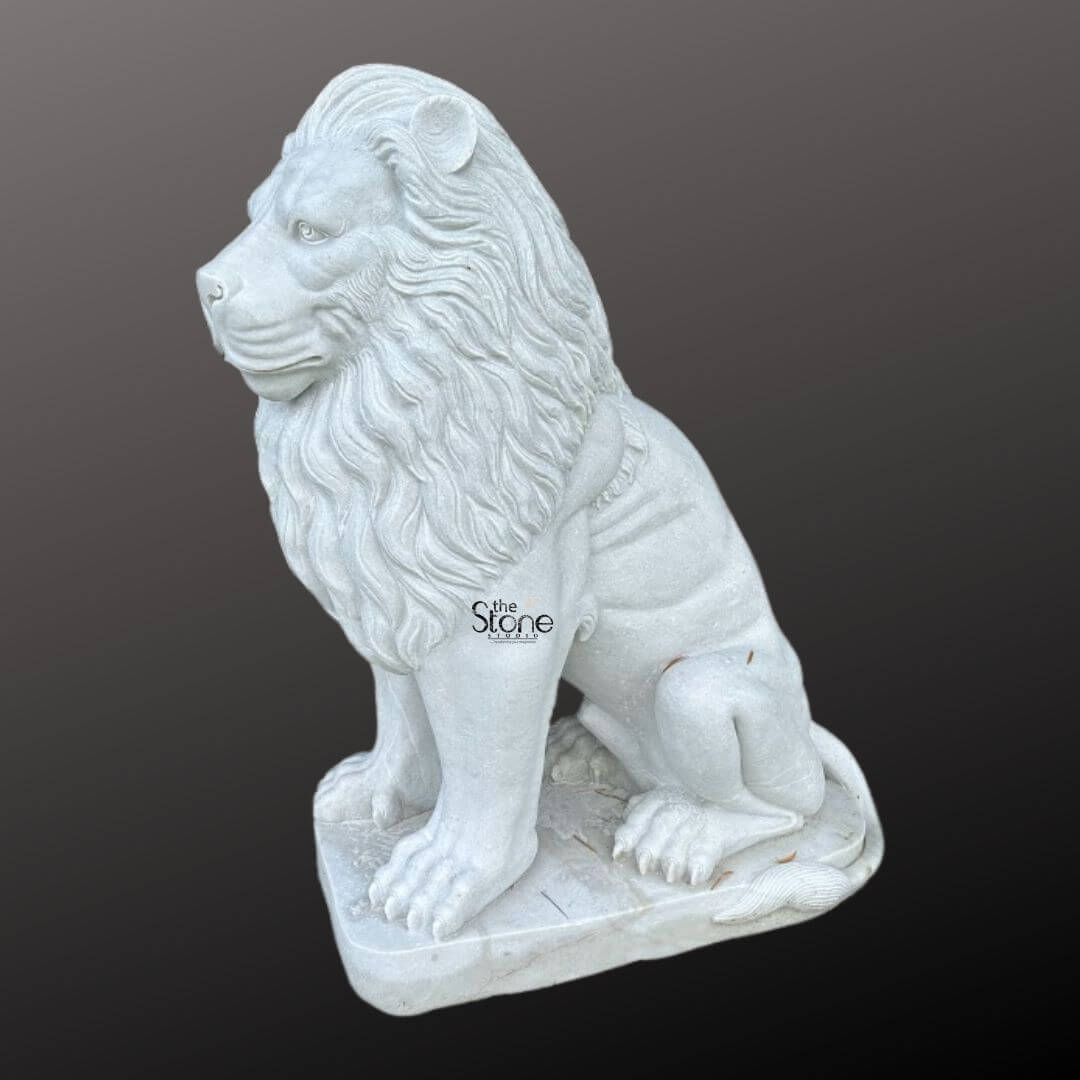 White Marble Lion Statue 5ft 7 A majestic marble lion statue is prominently displayed in a side profile against a dark gradient background embodying strength and regal elegance perfect for a home entrance. The lion is meticulously sculpted in a seated position with its powerful body held upright and its head turned to the left, gazing intently into the distance with a watchful and majestic demeanor. Its profile reveals a detailed and commanding expression with a strong jawline defined eyes and a prominent nose. The intricate carving brilliantly captures the texture of its flowing voluminous mane which cascades around its head neck, and shoulders conveying a sense of immense power and dignity ideal for welcoming guests. The statue is crafted from pristine white marble which exquisitely emphasizes the fine details of the carving, from the individual strands within the mane to the robust structure of its paws and the sharp definition of its claws. The smooth polished surface of the marble subtly reflects ambient light accentuating the contours and musculature of the lion's formidable form. The inherent beauty and purity of the white marble are showcased highlighting the exceptional skill of the artisan in bringing such a formidable creature to life in stone providing an impressive statement piece for a home entrance. The marble lion statue rests on a sturdy rectangular base also carved from matching white marble providing a solid foundation and integrating seamlessly with the overall design. This elegant sculpture captures the essence of a powerful guardian and a timeless symbol of royalty and strength, making it a captivating subject for an article exploring marble lion statues and their commanding presence when used for enhancing and embellishing a home entrance.
