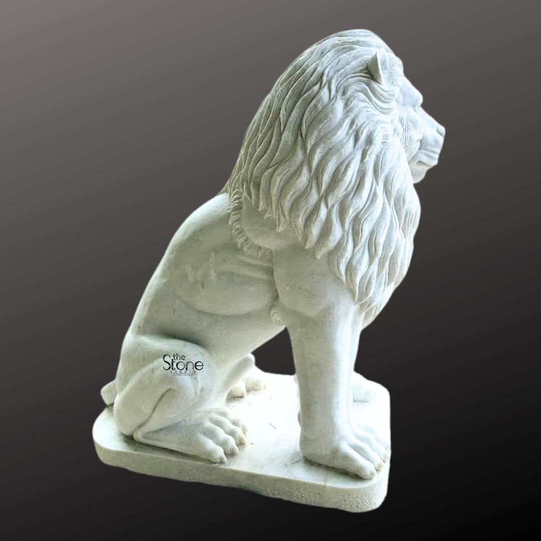 White Marble Lion Statue 5ft 8 A magnificent marble lion statue is prominently displayed in a side profile against a dark gradient background embodying strength and regal elegance making it an ideal choice for a villa entrance. The lion is meticulously sculpted in a commanding seated position with its powerful body held upright and its head turned to the right gazing intently into the distance with a watchful and majestic demeanor. Its profile reveals a detailed and commanding expression with a strong jawline defined eyes and a prominent nose. The intricate carving brilliantly captures the texture of its flowing voluminous mane which cascades around its head neck, and shoulders conveying a sense of immense power and dignity, perfectly befitting a grand entrance. The statue is crafted from pristine white marble which exquisitely emphasizes the fine details of the carving from the individual strands within the mane to the robust structure of its paws and the sharp definition of its claws. The smooth, polished surface of the marble subtly reflects ambient light accentuating the contours and musculature of the lion's formidable form. The inherent beauty and purity of the white marble are showcased highlighting the exceptional skill of the artisan in bringing such a formidable creature to life in stone providing an impressive and classic statement piece for a villa entrance. The marble lion statue rests on a sturdy rectangular base also carved from matching white marble providing a solid foundation and integrating seamlessly with the overall design. This elegant sculpture captures the essence of a powerful guardian and a timeless symbol of royalty and strength making it a captivating subject for an article exploring marble lion statues and their commanding presence when used for enhancing and embellishing a villa entrance.
