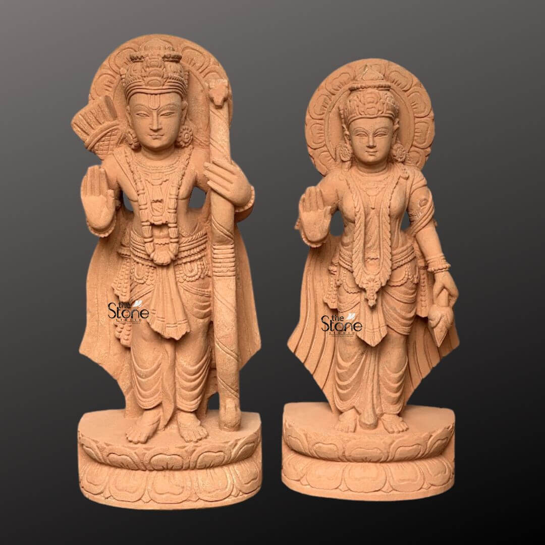 Ram Darbar Idol for Home Temple 2ft 8 A pair of magnificent 2-foot sandstone statues of Lord Rama and Sita from a Ram Darbar set are elegantly displayed against a dark gradient background making them ideal for a pooja room. Lord Rama on the left stands in a noble posture his right hand raised in a gesture of blessing while he holds his bow and arrow symbolizing protection and righteousness. Beside him Sita on the right also stands gracefully her hand raised in a similar gesture of blessing radiating purity and devotion. Both deities are adorned with elaborate crowns intricate jewelry and flowing traditional garments all meticulously carved from the warm earthy sandstone. Behind the heads of both Rama and Sita circular halo-like structures are intricately carved with traditional patterns further accentuating their divine aura and spiritual significance within a sacred space. The craftsmanship is evident in every detail from the serene expressions on their faces to the delicate folds of their attire and the intricate patterns of their ornaments. The sandstone's natural texture and warm hue give the statues an authentic, ancient feel, enriching their spiritual presence and highlighting the artisans' skill, making them visually compelling for a pooja room. Each figure stands on a multi-layered circular base also carved from sandstone featuring delicate lotus petal motifs. These sturdy bases provide a strong aesthetic foundation and elevate the statues making them prominent display pieces. This pair of 2-foot sandstone statues representing the divine couple of the Ram Darbar captures the essence of divine heroism and unwavering devotion making them a captivating subject for an article exploring such intricately crafted and spiritually significant sculptures for a pooja room.