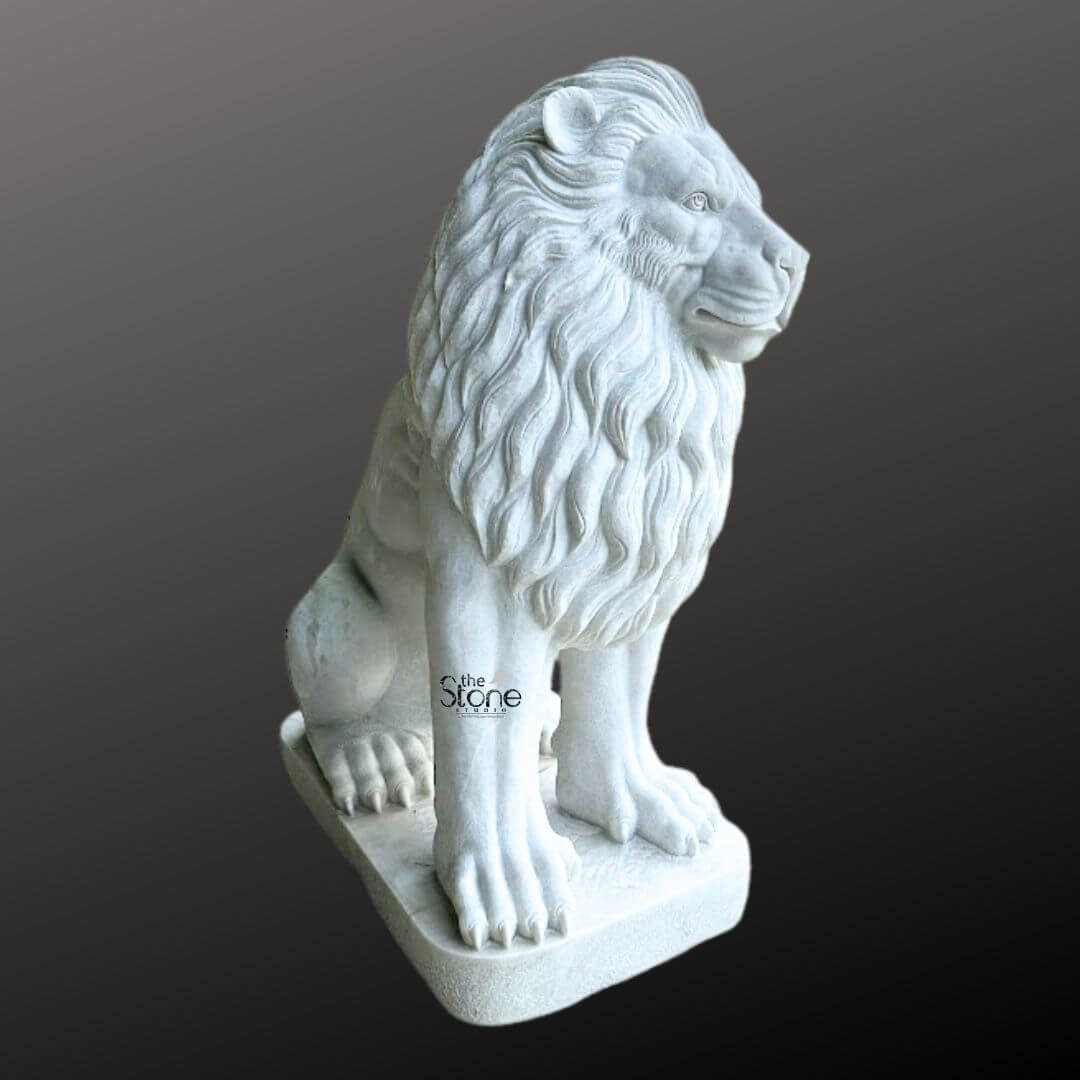 White Marble Lion Statue 5ft 10 A magnificent white marble lion sculpture is prominently displayed in a side profile against a dark gradient background serving as a prime example for an article on white marble lion sculptures. The lion is meticulously sculpted in a regal seated position with its powerful body held upright and its head turned to the right gazing intently into the distance with a watchful and majestic demeanor. Its profile reveals a detailed and commanding expression with a strong jawline defined eyes and a prominent nose. The intricate carving brilliantly captures the texture of its flowing, voluminous mane which cascades around its head neck and shoulders conveying a sense of immense power and dignity. The sculpture is crafted from pristine white marble which exquisitely emphasizes the fine details of the carving from the individual strands within the mane to the robust structure of its paws and the sharp definition of its claws. The smooth, polished surface of the marble subtly reflects ambient light accentuating the contours and musculature of the lion's formidable form. The inherent beauty and purity of the white marble are showcased highlighting the exceptional skill of the artisan in transforming raw stone into such a lifelike and commanding figure. The white marble lion sculpture rests on a sturdy rectangular base also carved from matching white marble providing a solid foundation and integrating seamlessly with the overall design. This elegant sculpture captures the essence of a powerful guardian and a timeless symbol of royalty and strength making it a captivating subject for an article exploring white marble lion sculptures their commanding presence and their use in grand architectural or decorative settings.
