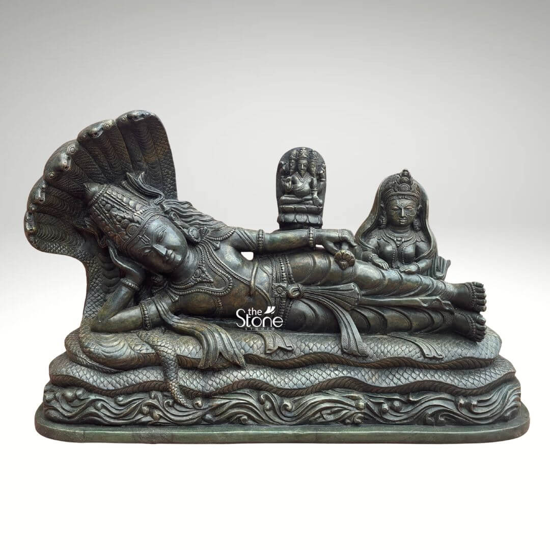 Ananta Shayana Vishnu Statue 20" 1 A magnificent greenstone statue depicts Lord Vishnu in his iconic Ananta Shayana posture a powerful representation of cosmic dissolution and creation. The grand statue showcases Vishnu reclining on the coils of Sheshnag the multi-headed serpent whose fanned hoods provide a majestic canopy over Vishnu's head. The deep rich green hue of the stone possibly a dark serpentine or chlorite schist imparts an ancient and mystical aura to the intricate carving making it a compelling piece for both spiritual reverence and artistic appreciation. Lord Vishnu is carved with serene features his eyes gently closed in cosmic slumber symbolizing the period between universal cycles. He is richly adorned with traditional jewelry including a crown necklaces armlets and a sacred thread all meticulously detailed. From his navel emerges a small lotus flower upon which sits a smaller idol of Brahma the creator god illustrating the cyclical nature of creation as Brahma emerges from Vishnu's cosmic dream. To Vishnu's right seated reverently at his feet is Goddess Lakshmi his consort depicted with equally elaborate adornments and a pose of devoted service. This greenstone Ananta Shayana Vishnu statue is a profound representation of cosmic order preservation and the continuous cycle of time in Hindu cosmology. The exceptional detail and the choice of greenstone often associated with wisdom and healing enhance its spiritual potency. This statue embodying the very essence of Vishnu's role as the preserver is an impressive and deeply meaningful artifact ideal for a grand temple a prominent home altar or as a centerpiece in a spiritual garden inviting contemplation and reverence for the divine cosmic dance.
